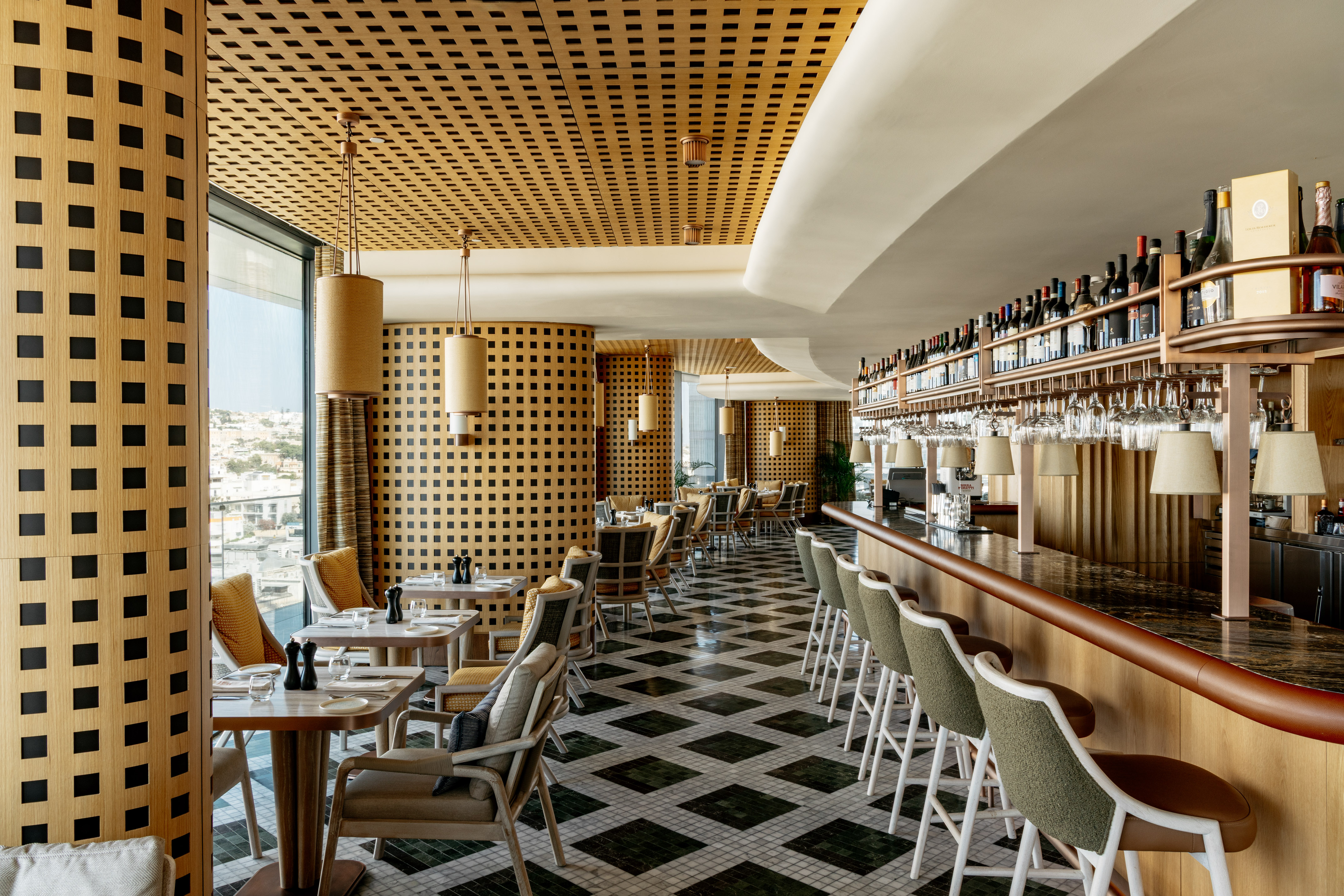 Modern restaurant bar with geometric wooden walls, checkered floor, and city view.