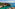 Turquoise bay with sandy beach, pine-covered cliffs, and terracotta roofs.