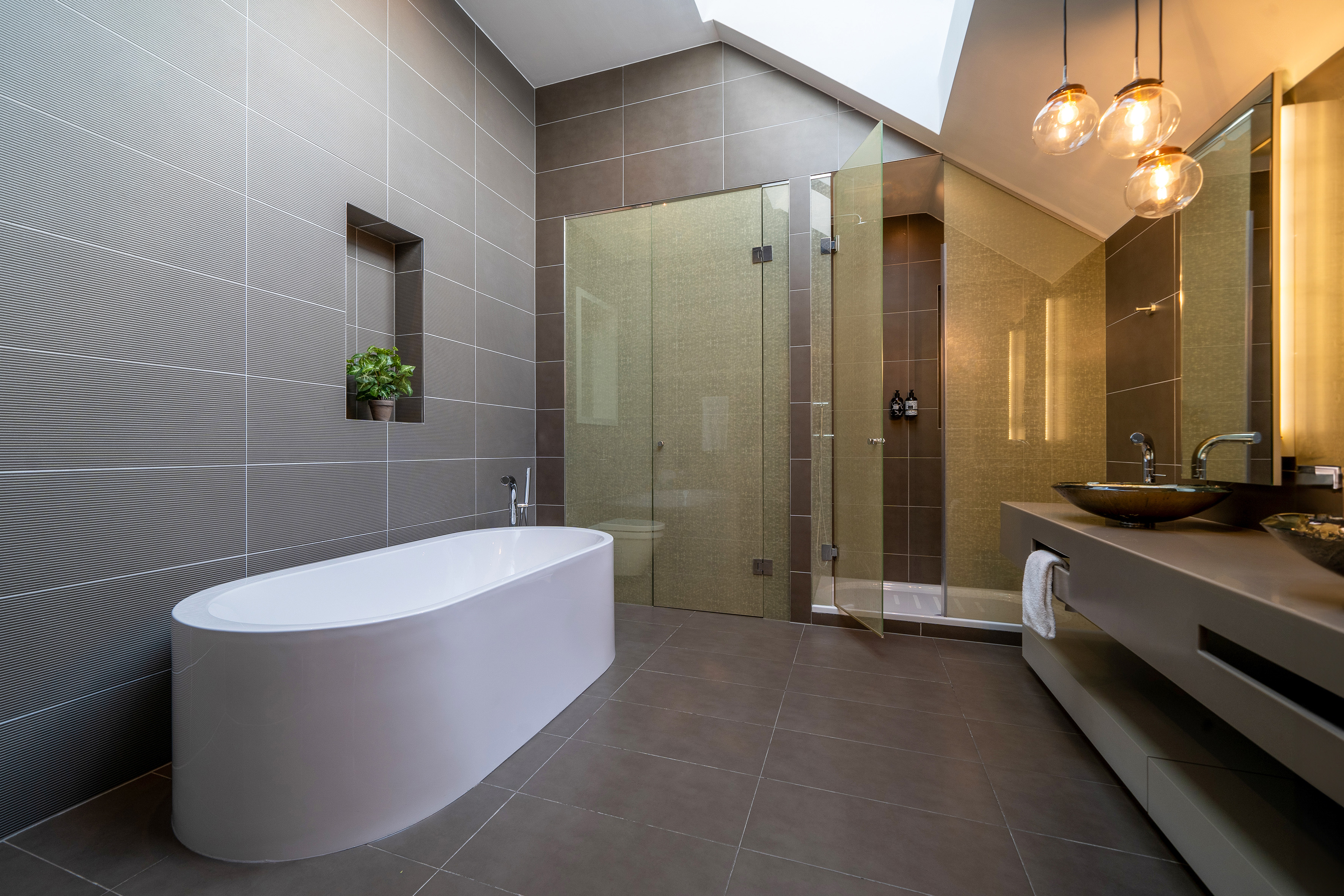 Modern gray bathroom with freestanding tub, glass shower, and vanity.