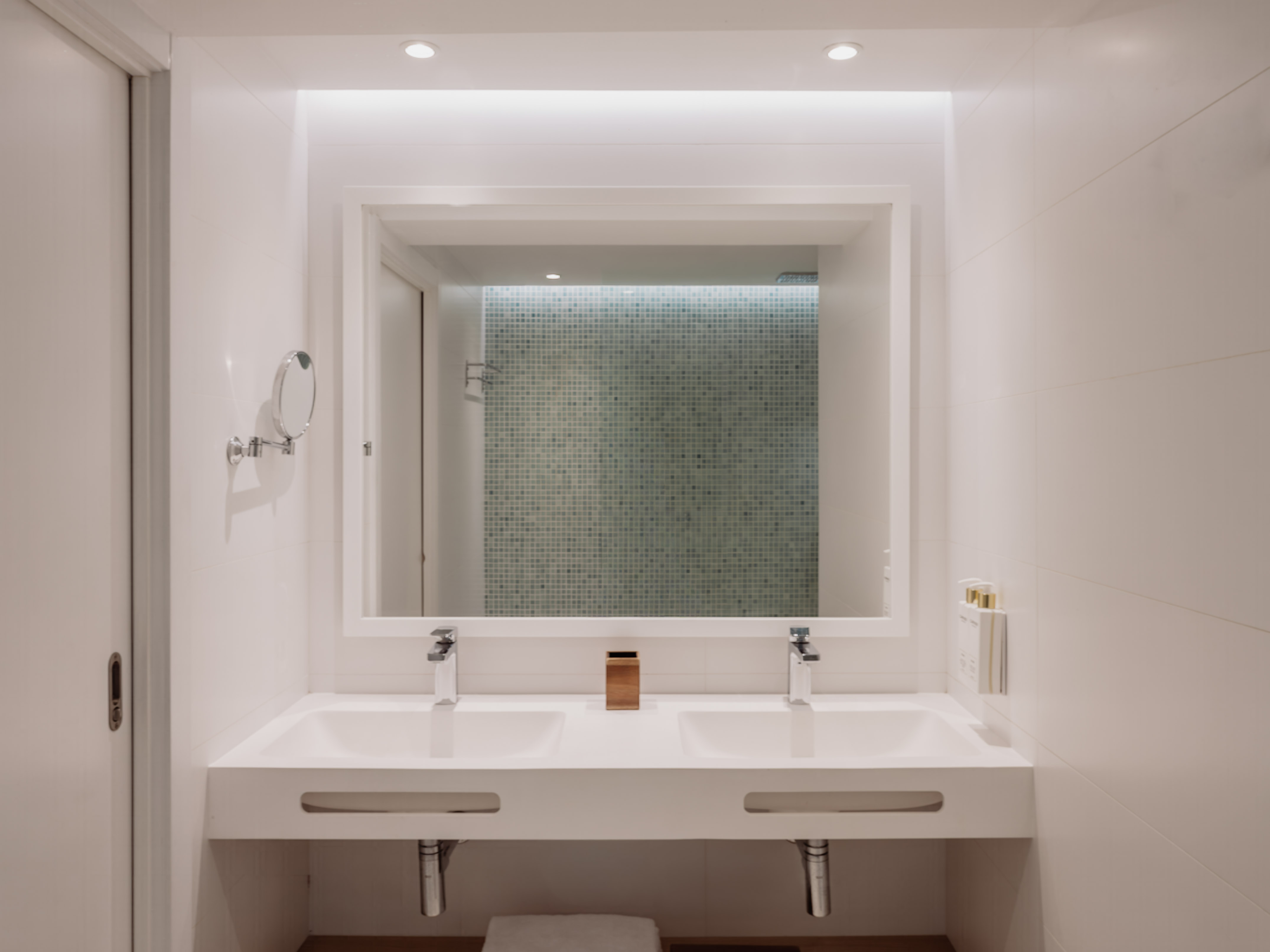Baño moderno, doble lavabo blanco, espejo iluminado. Diseño minimalista hotel.