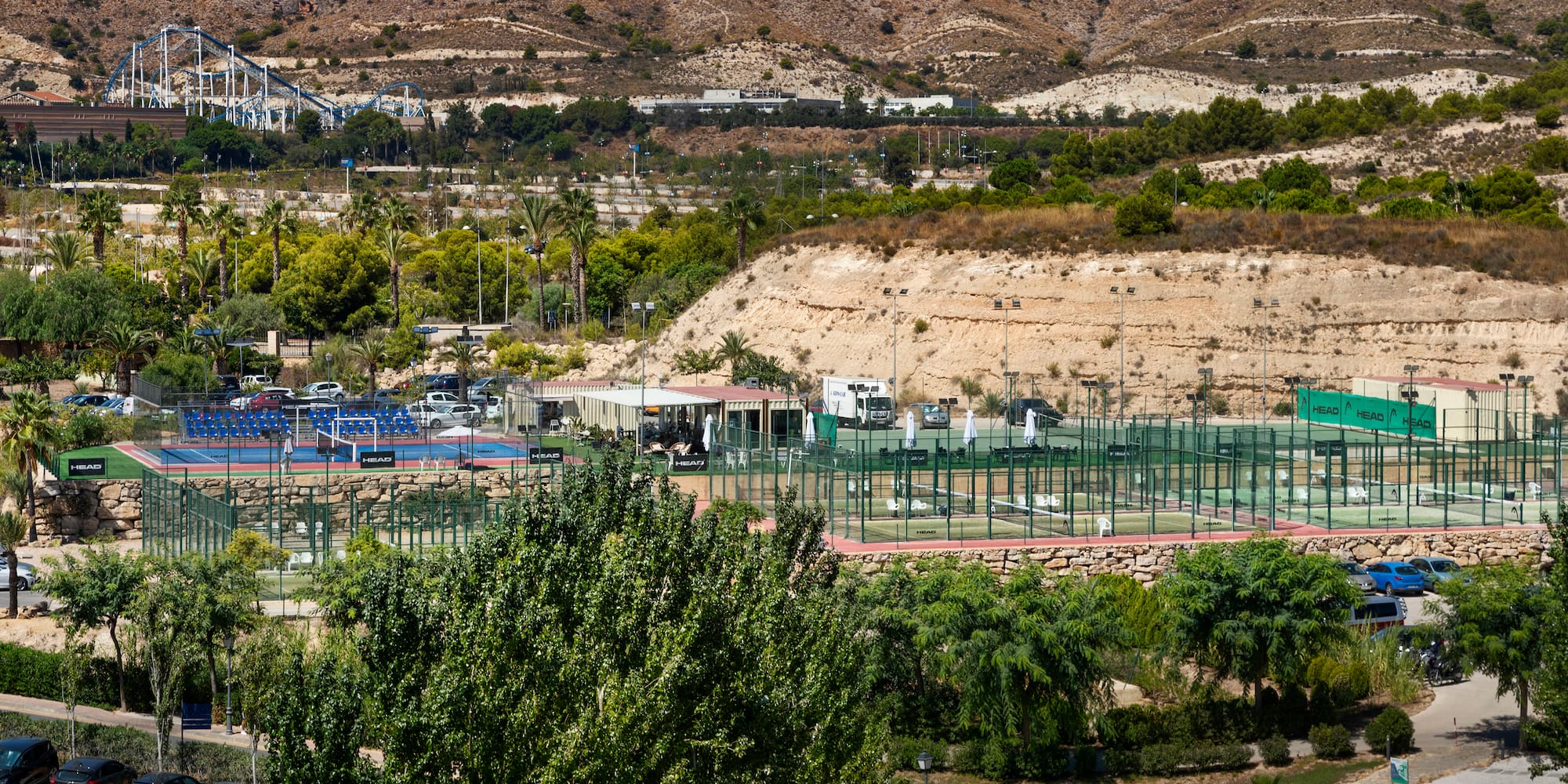 a tennis court with trees and mountains in the background