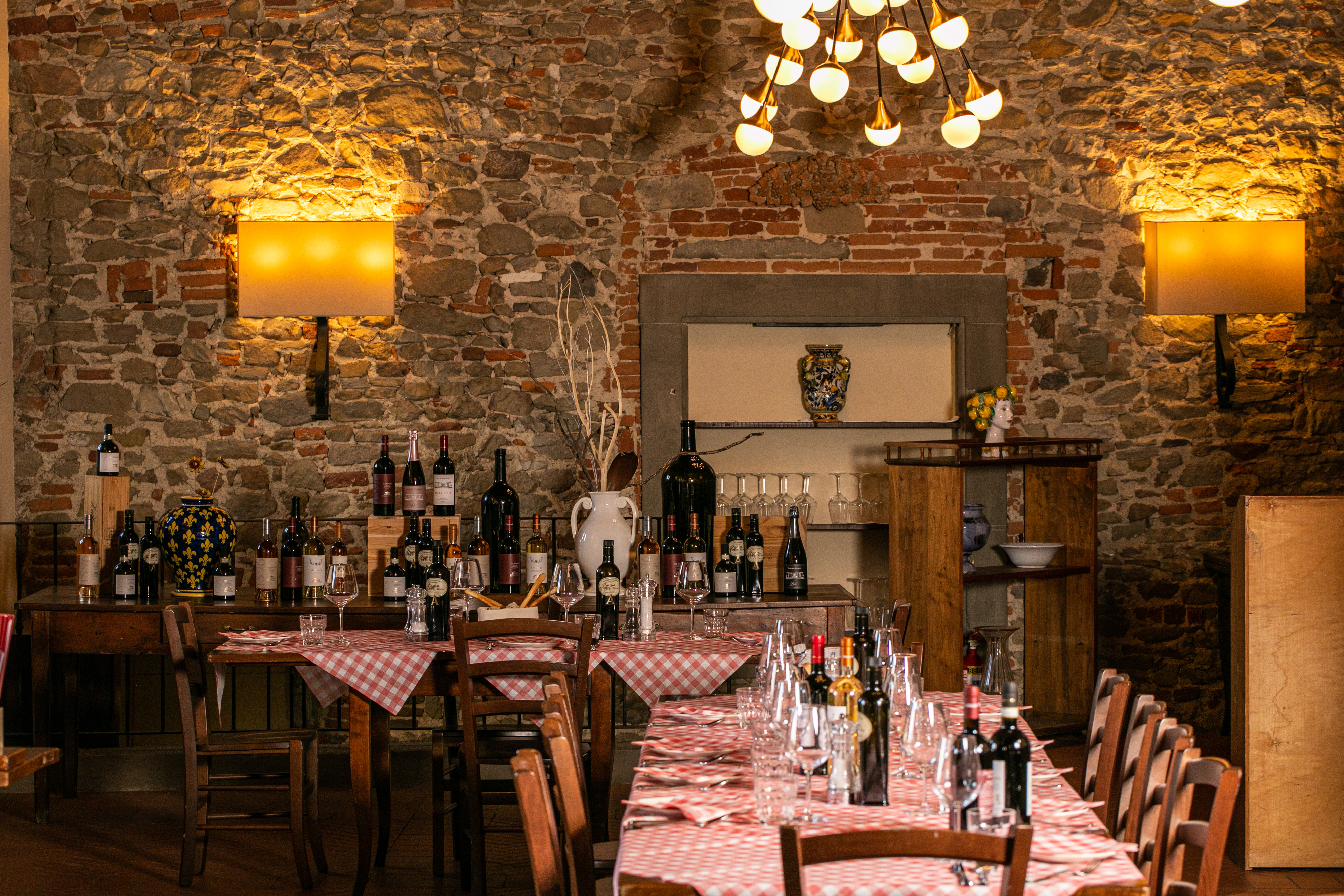 Rustic Italian restaurant with stone walls, checkered tables, and wine bottles.
