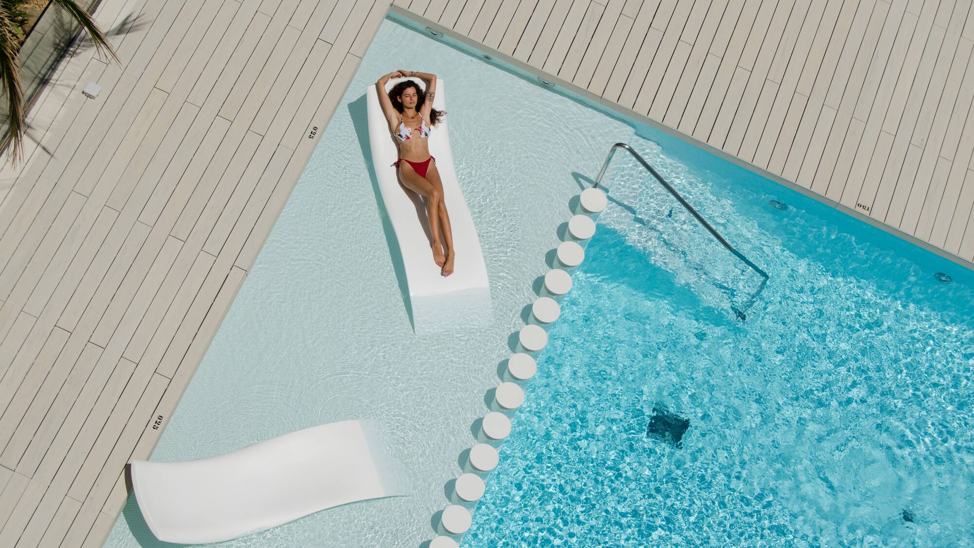 a woman in a garment lying on a floating bed next to a pool