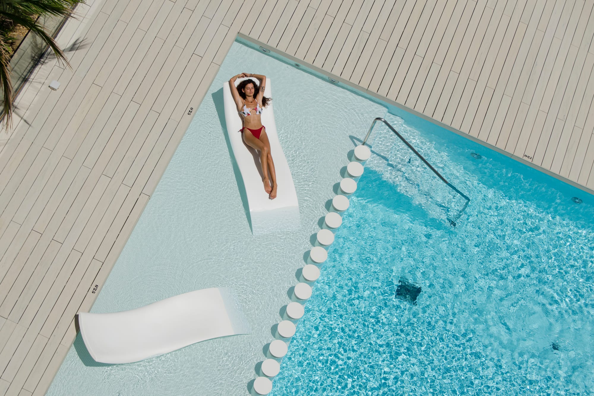 a woman in a garment lying on a floating bed next to a pool