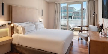 a bed with a chair and a desk in a hotel room