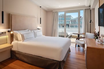 a bed with a chair and a desk in a hotel room