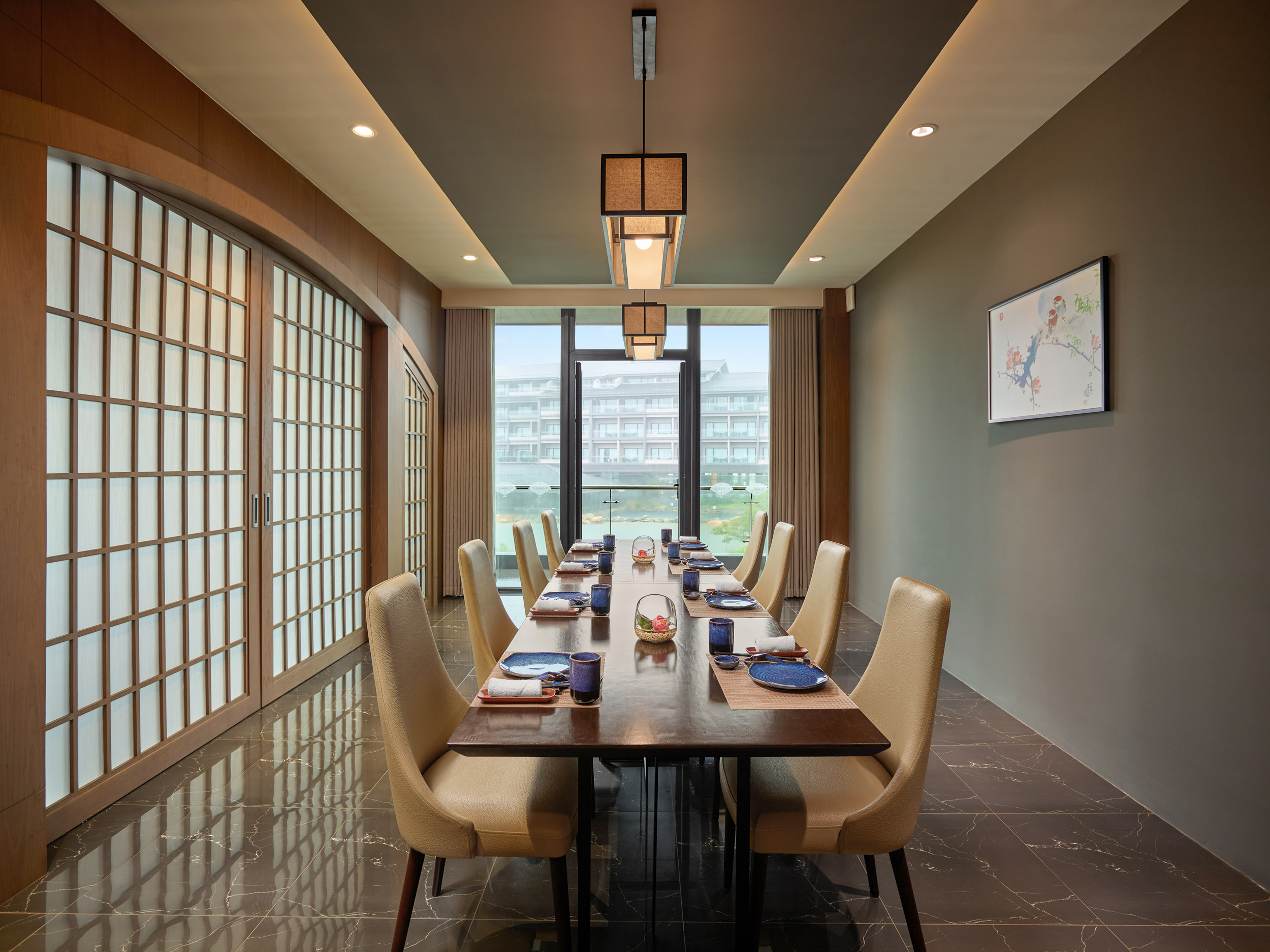 Modern private dining room, long table, beige chairs, Asian decor, window view.