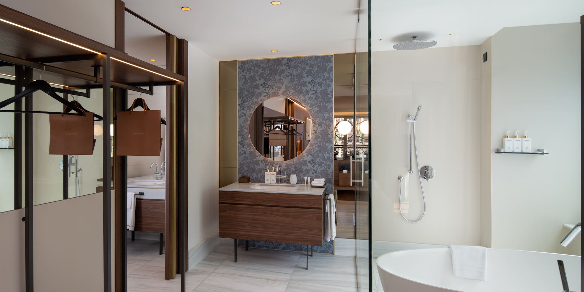 Modern hotel bathroom with walk-in shower, freestanding tub, wood vanity, marble.
