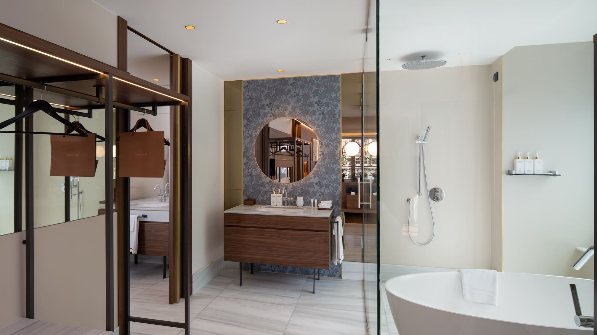 Modern hotel bathroom with walk-in shower, freestanding tub, wood vanity, marble.
