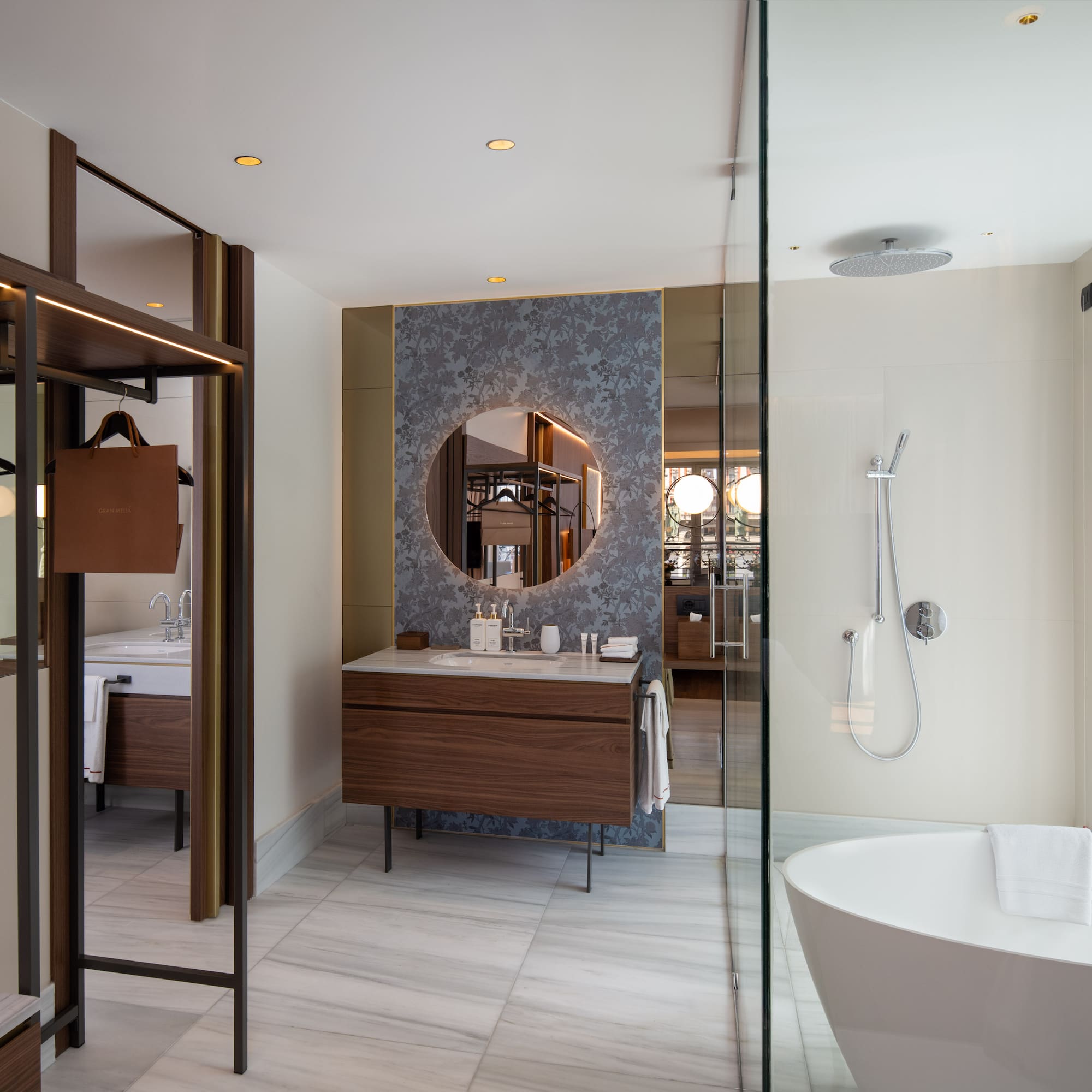 Modern hotel bathroom with walk-in shower, freestanding tub, wood vanity, marble.