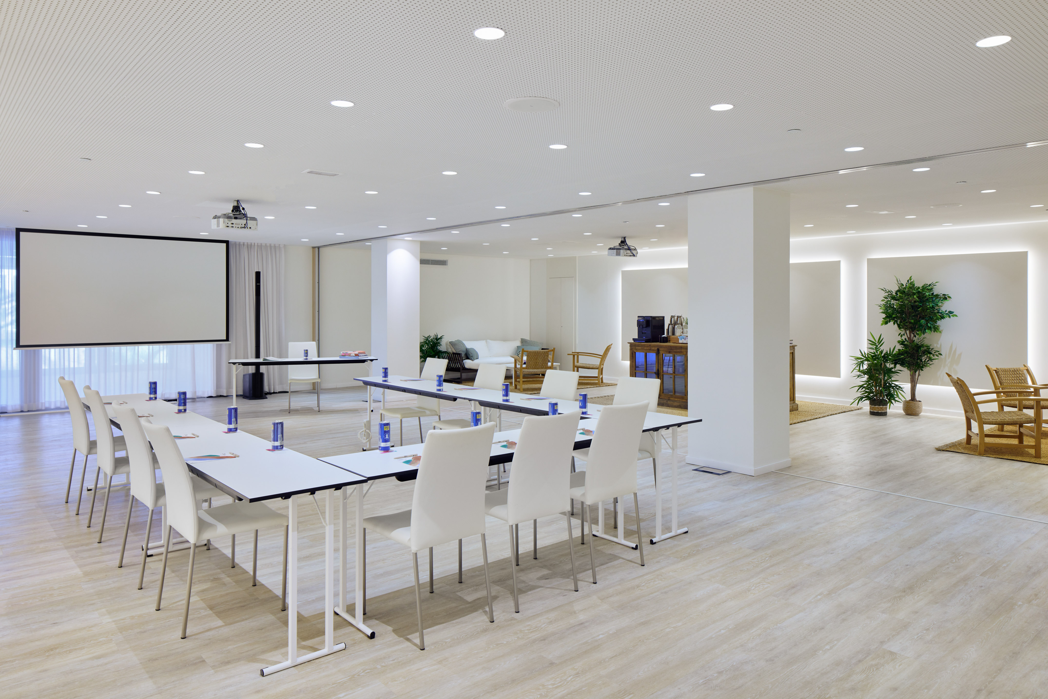 Modern, bright conference room with projector screen, tables, and lounge.