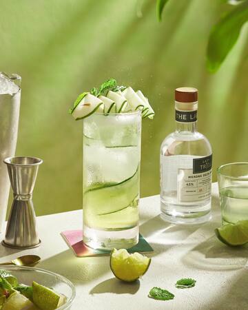 a glass of liquid with slices of apple on top and a bottle of alcohol