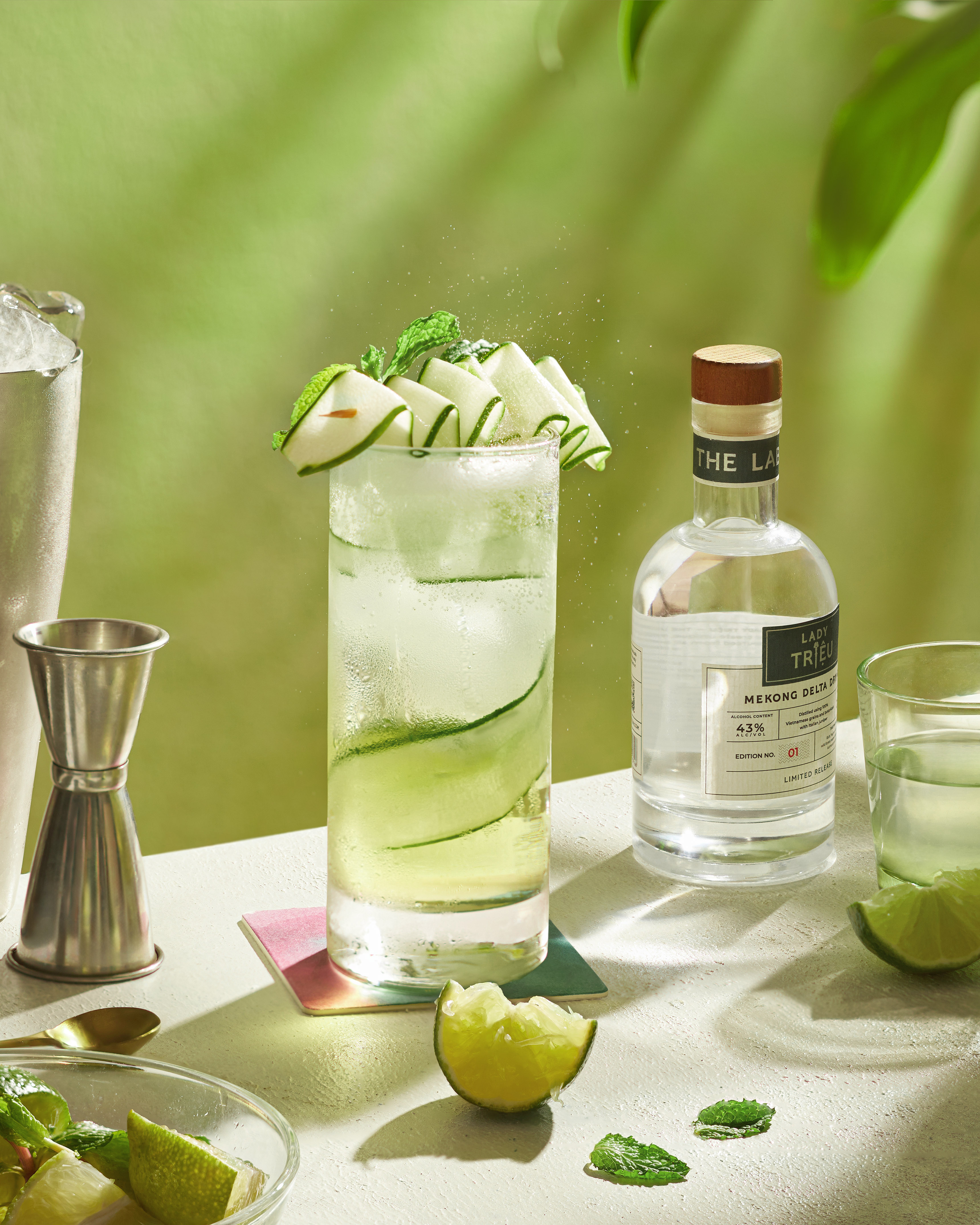 Refreshing Lady Triệu gin and cucumber cocktail with mint garnish and bottle.