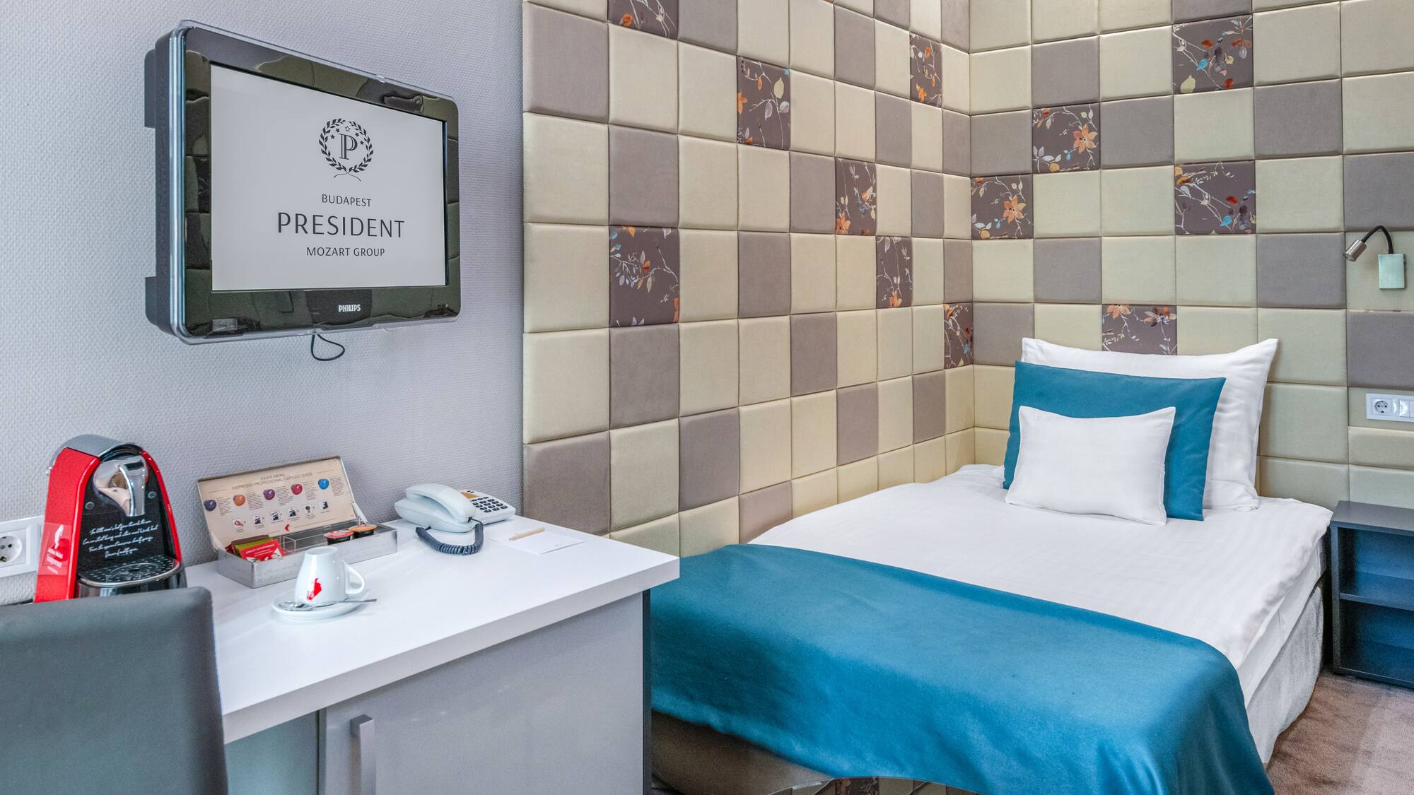 a bed with a blue blanket and a white desk