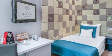 a bed with a blue blanket and a white desk