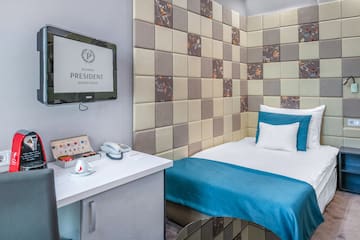 a bed with a blue blanket and a white desk