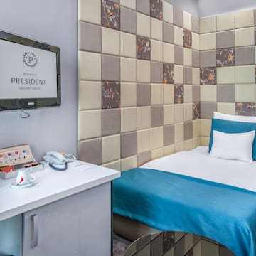 a bed with a blue blanket and a white desk