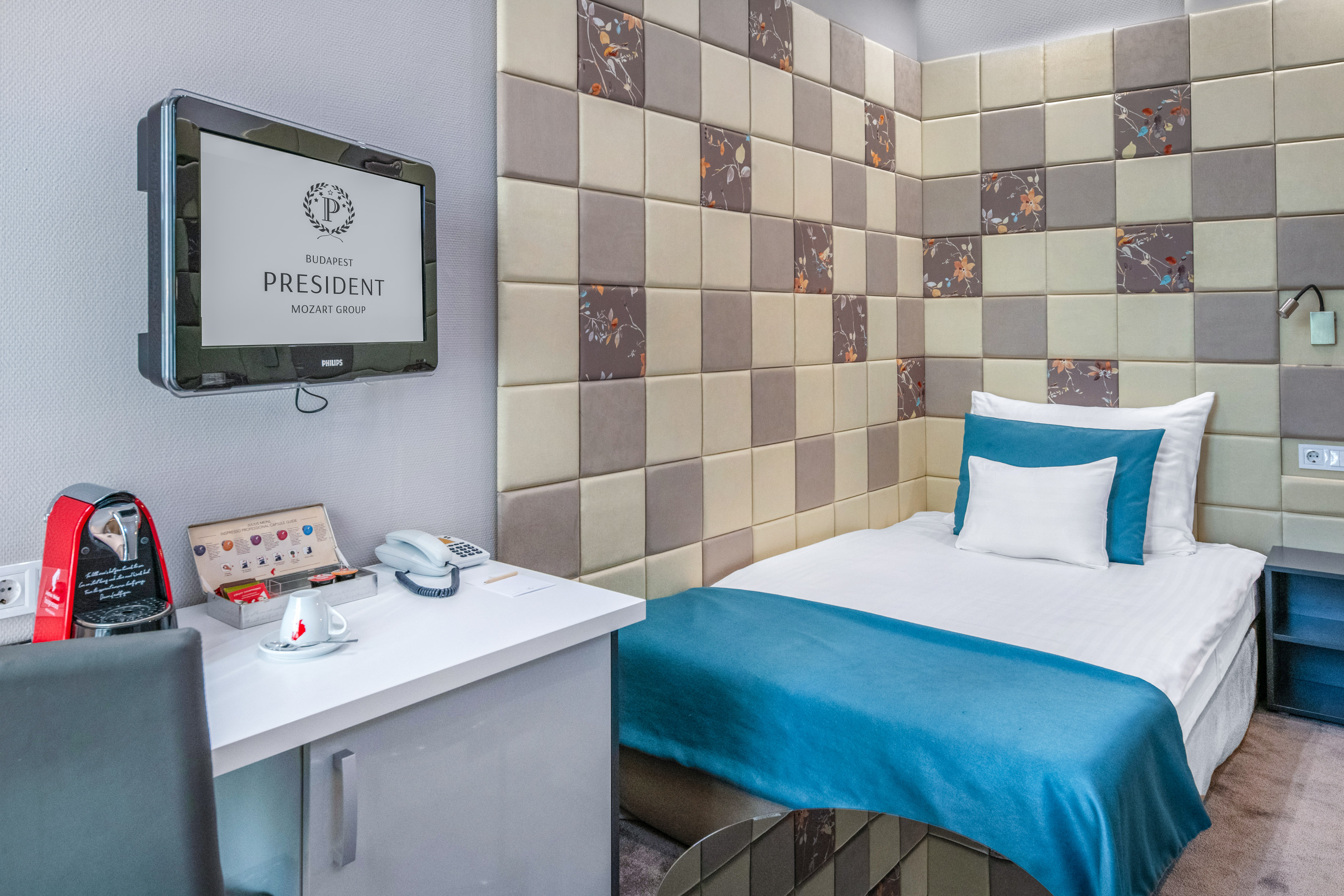 a bed with a blue blanket and a white desk