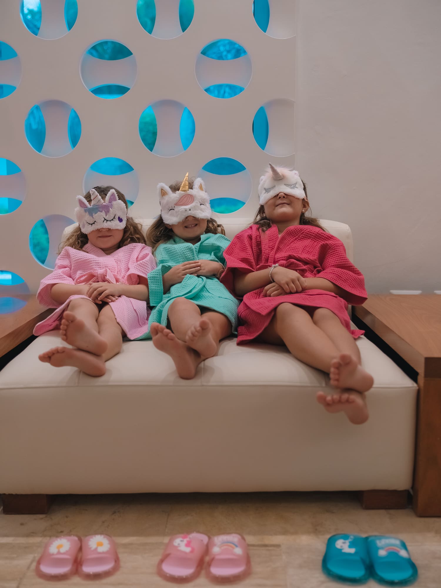 a group of girls sitting on a couch wearing unicorn masks