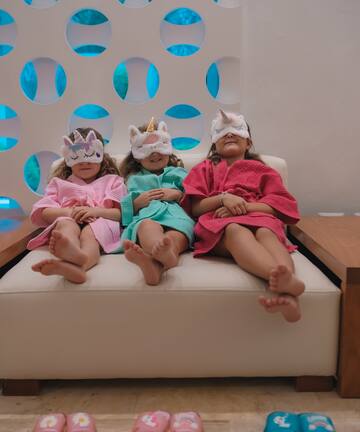 a group of girls sitting on a couch wearing unicorn masks