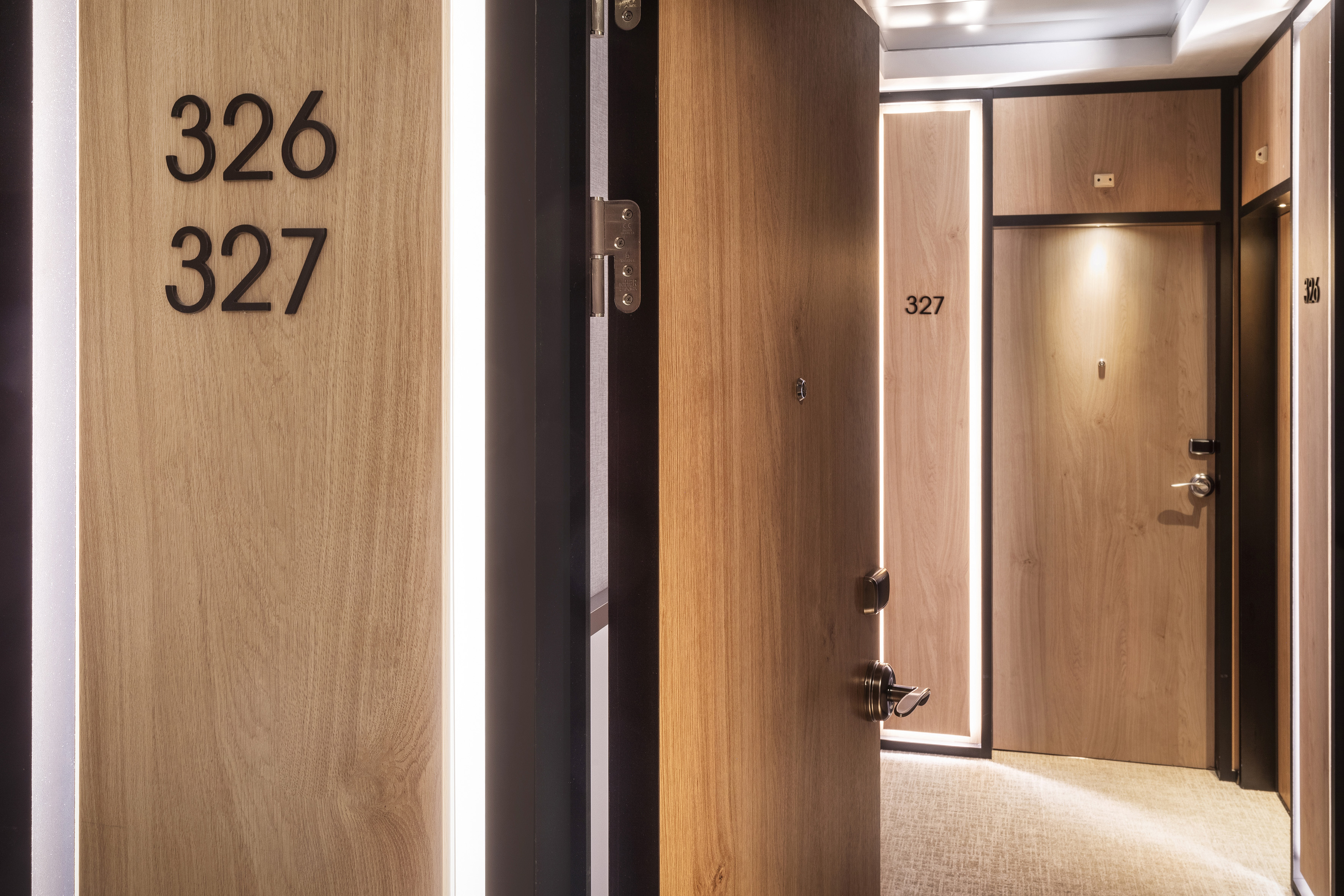 Modern hotel doors 326, 327 in an illuminated wooden hallway.