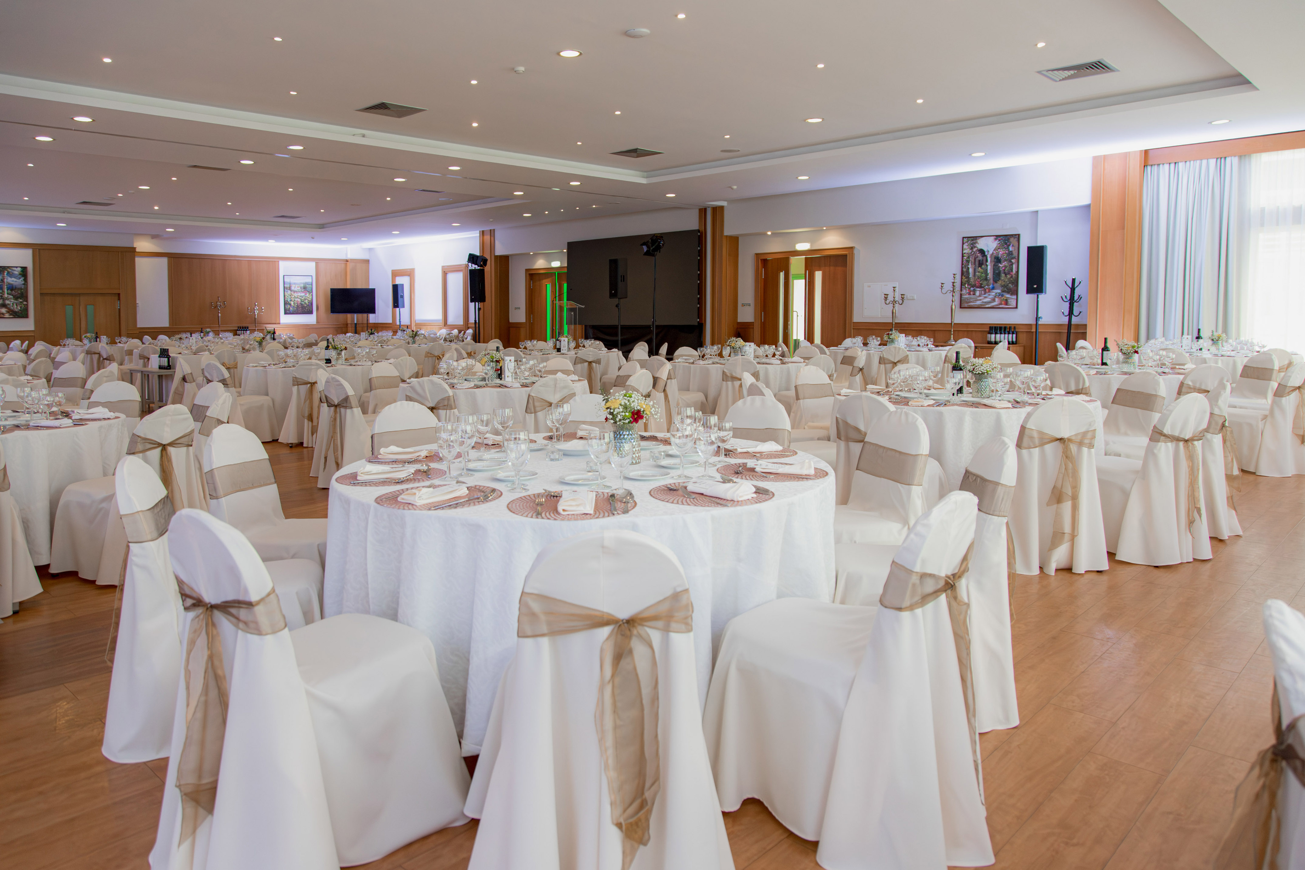 Elegant banquet hall with white tables, chair covers, and dining setup.