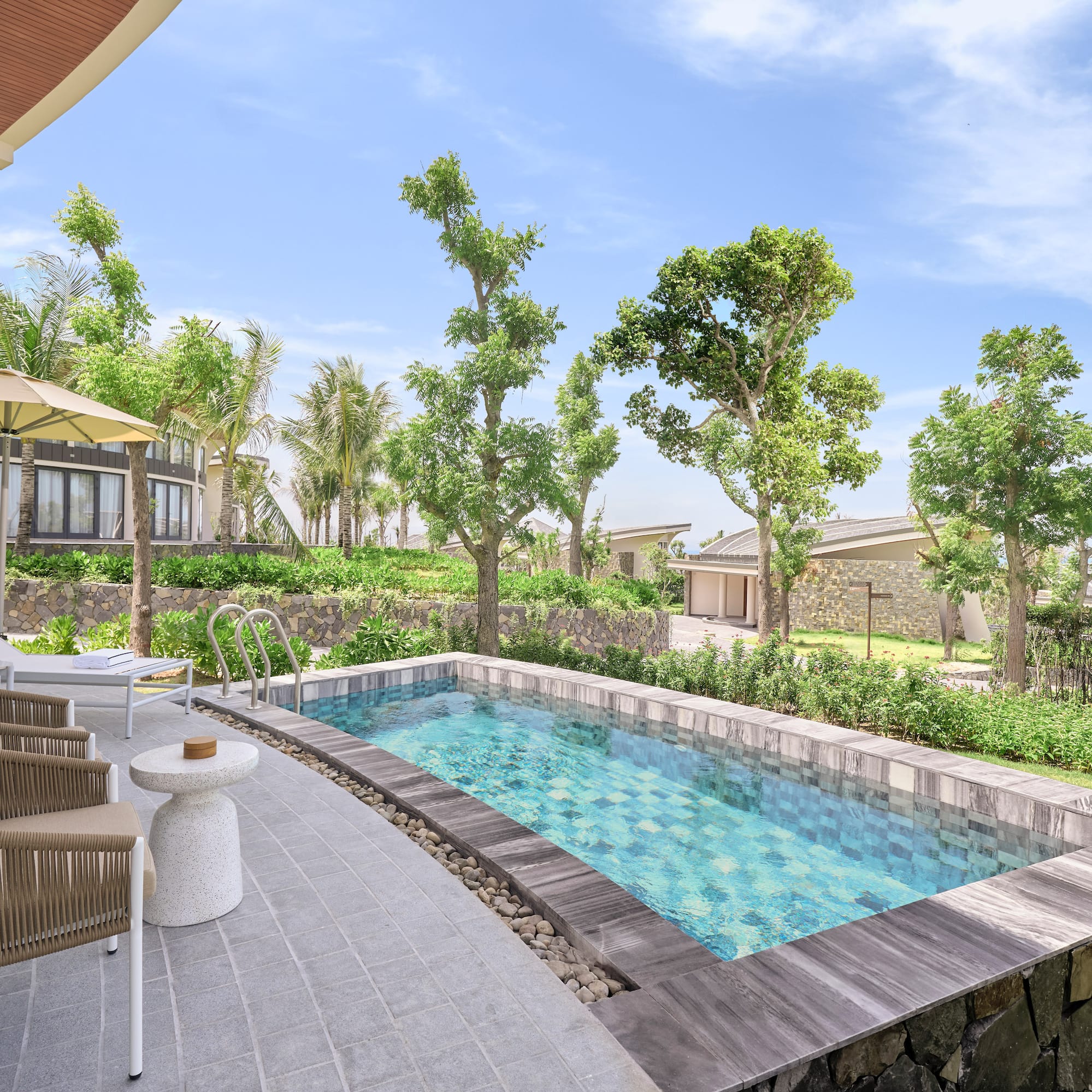 Private plunge pool at a modern resort villa with patio and lush garden.
