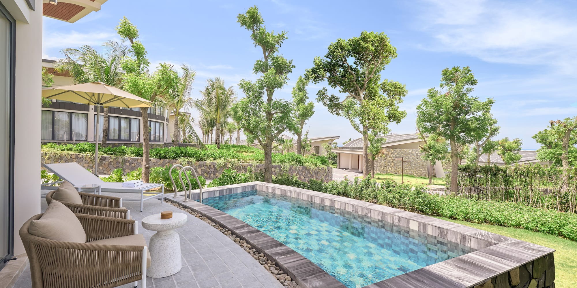 Private plunge pool at a modern resort villa with patio and lush garden.