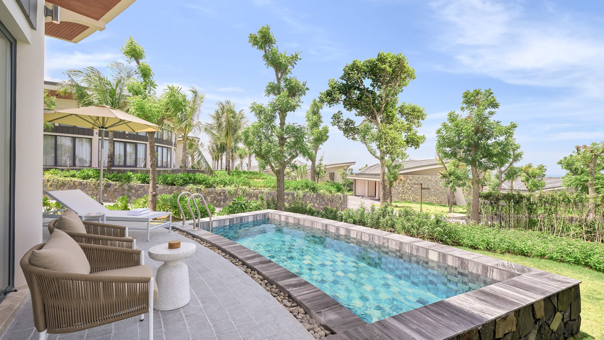 Private plunge pool at a modern resort villa with patio and lush garden.