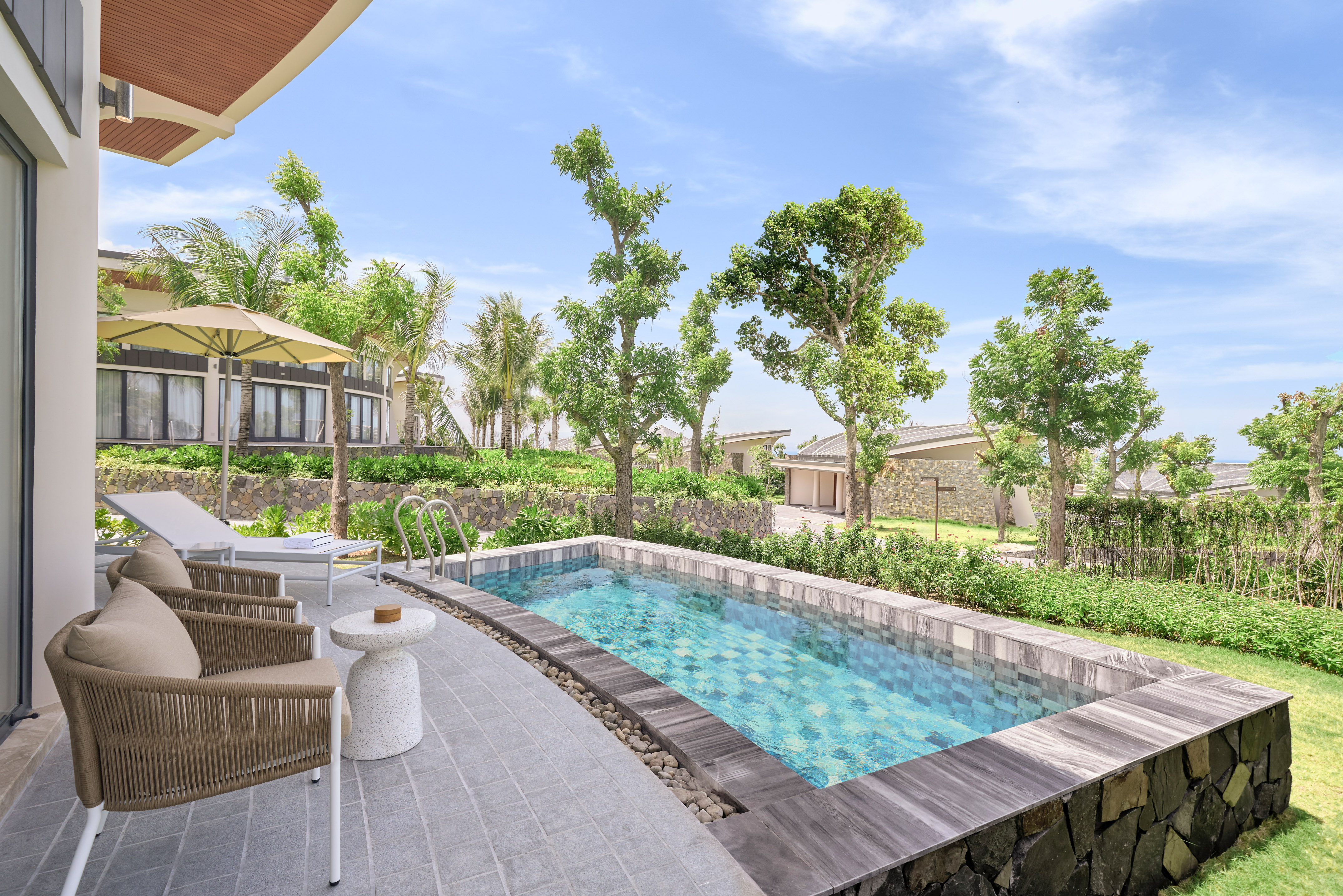 Private plunge pool at a modern resort villa with patio and lush garden.