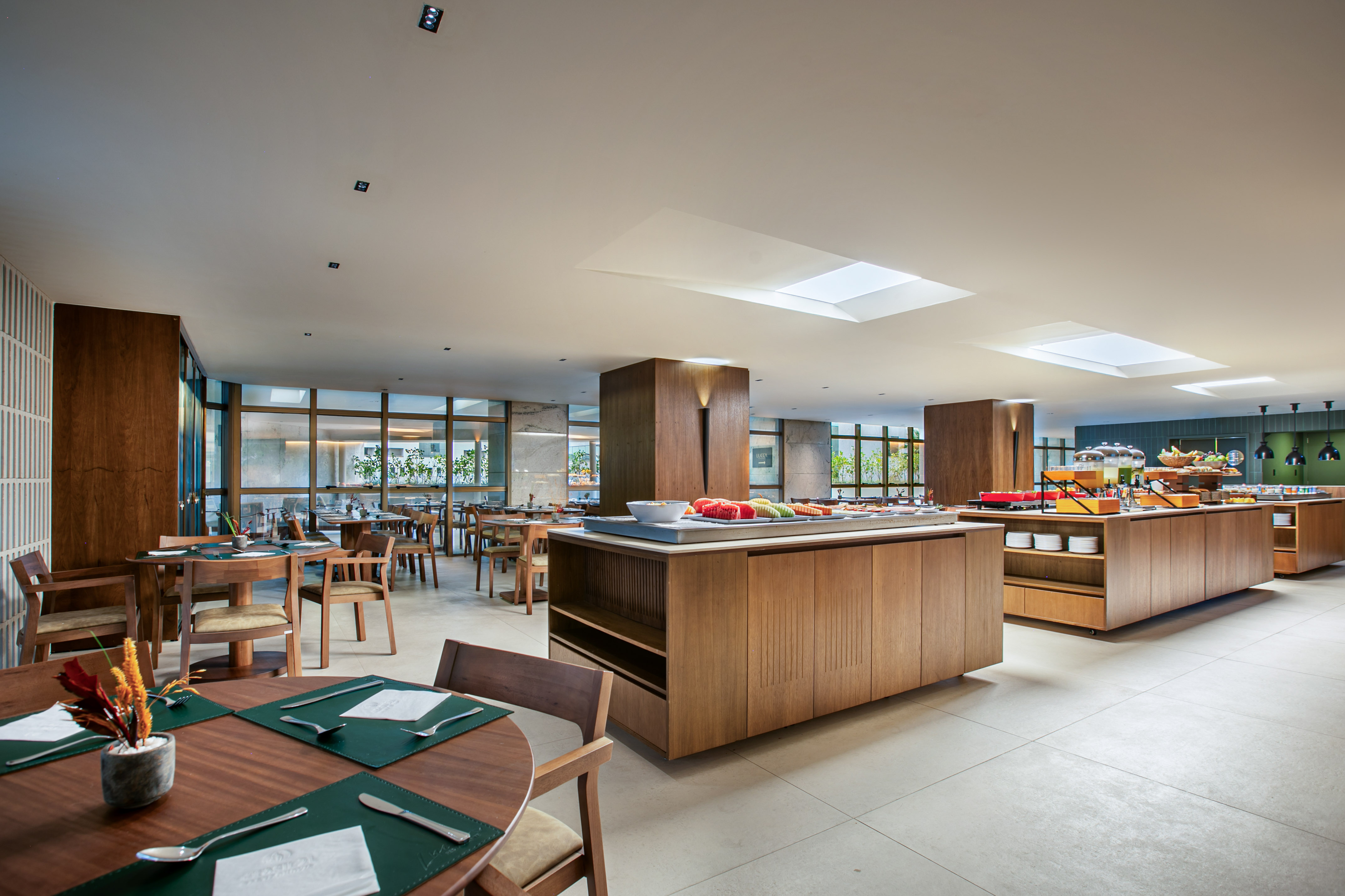 Spacious modern hotel dining room with breakfast buffet and wooden tables.