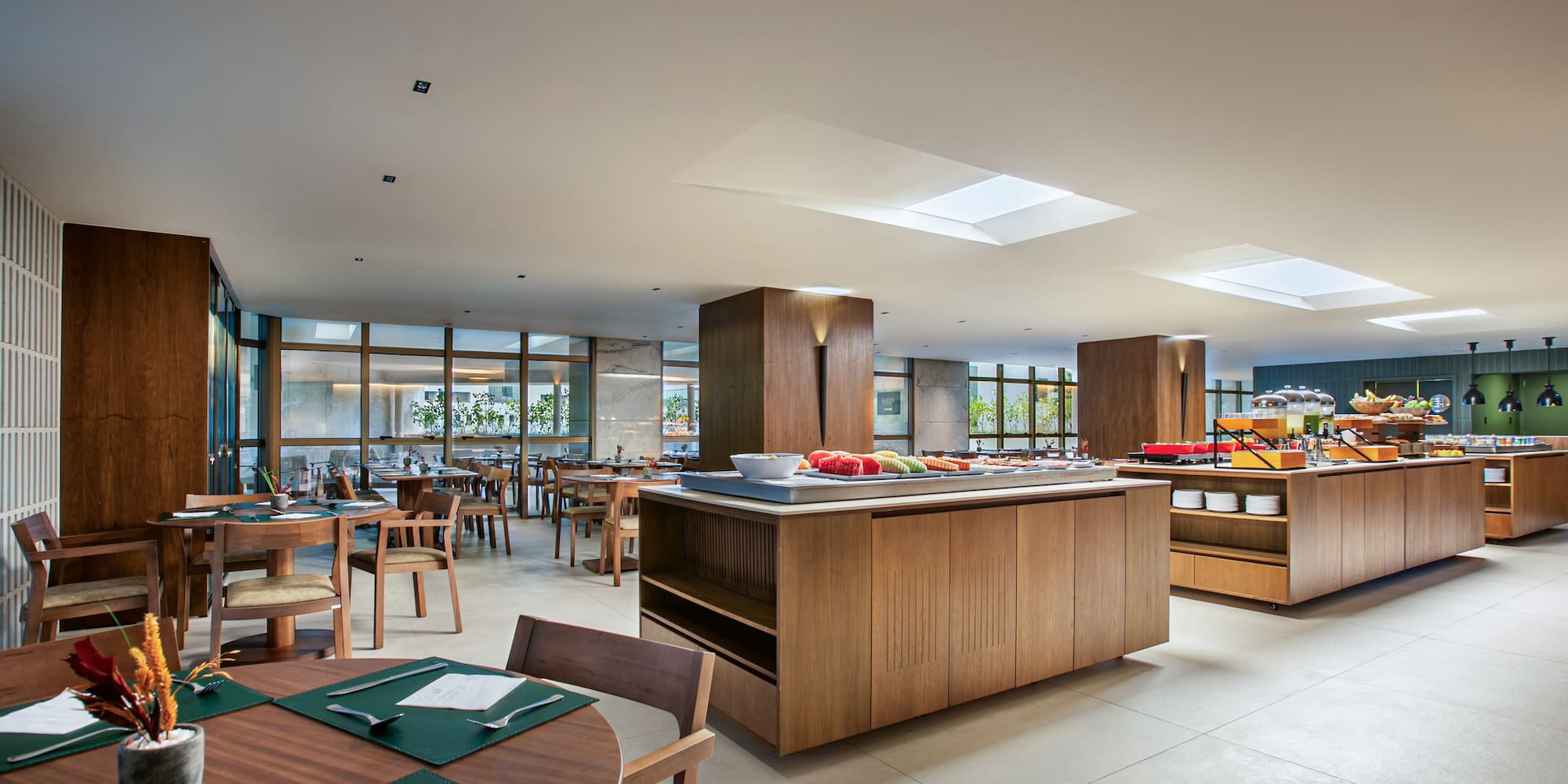 Spacious modern hotel dining room with breakfast buffet and wooden tables.