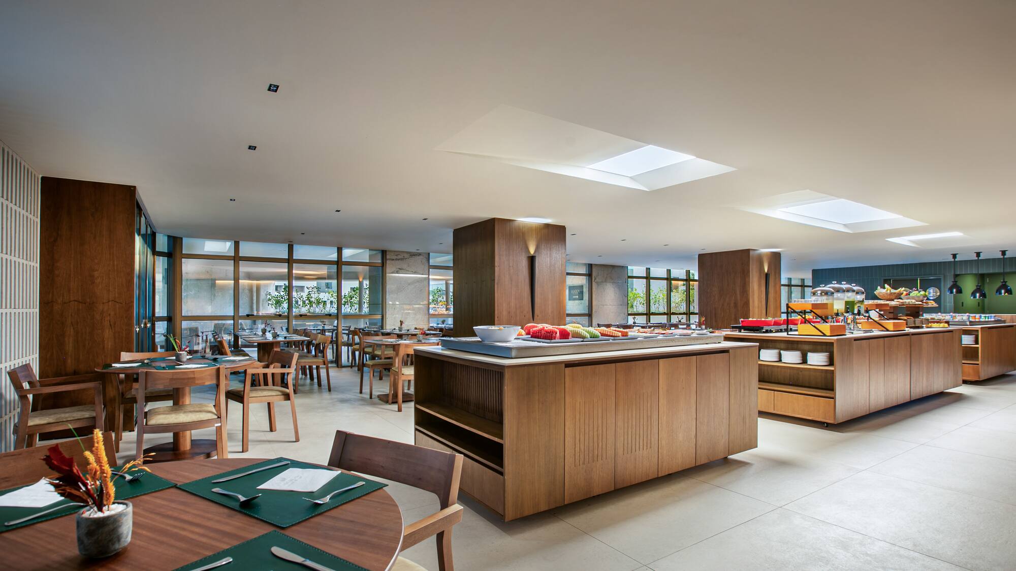 Spacious modern hotel dining room with breakfast buffet and wooden tables.