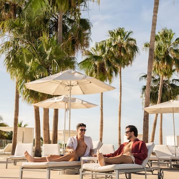 two men sitting on lounge chairs under umbrellas