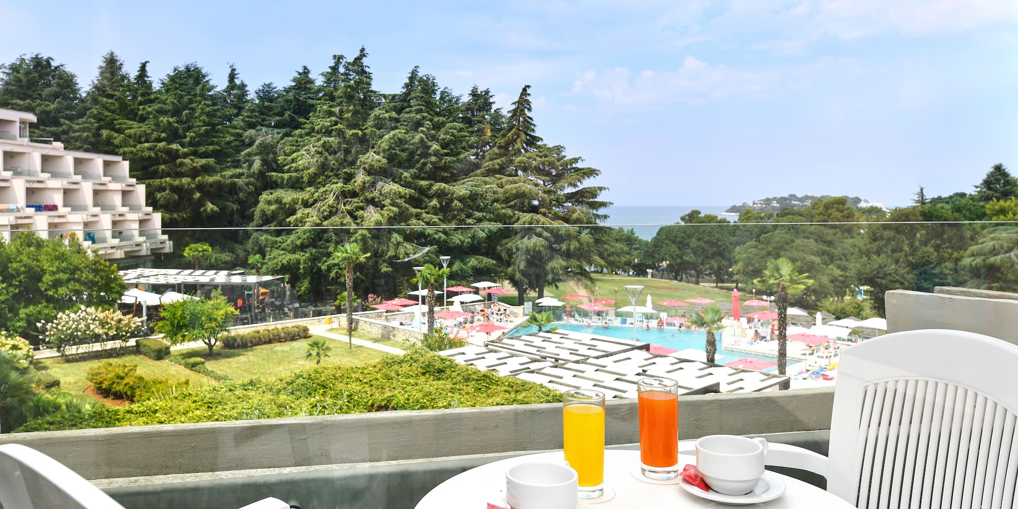 a table with a cup and saucer on it with a view of a pool and trees
