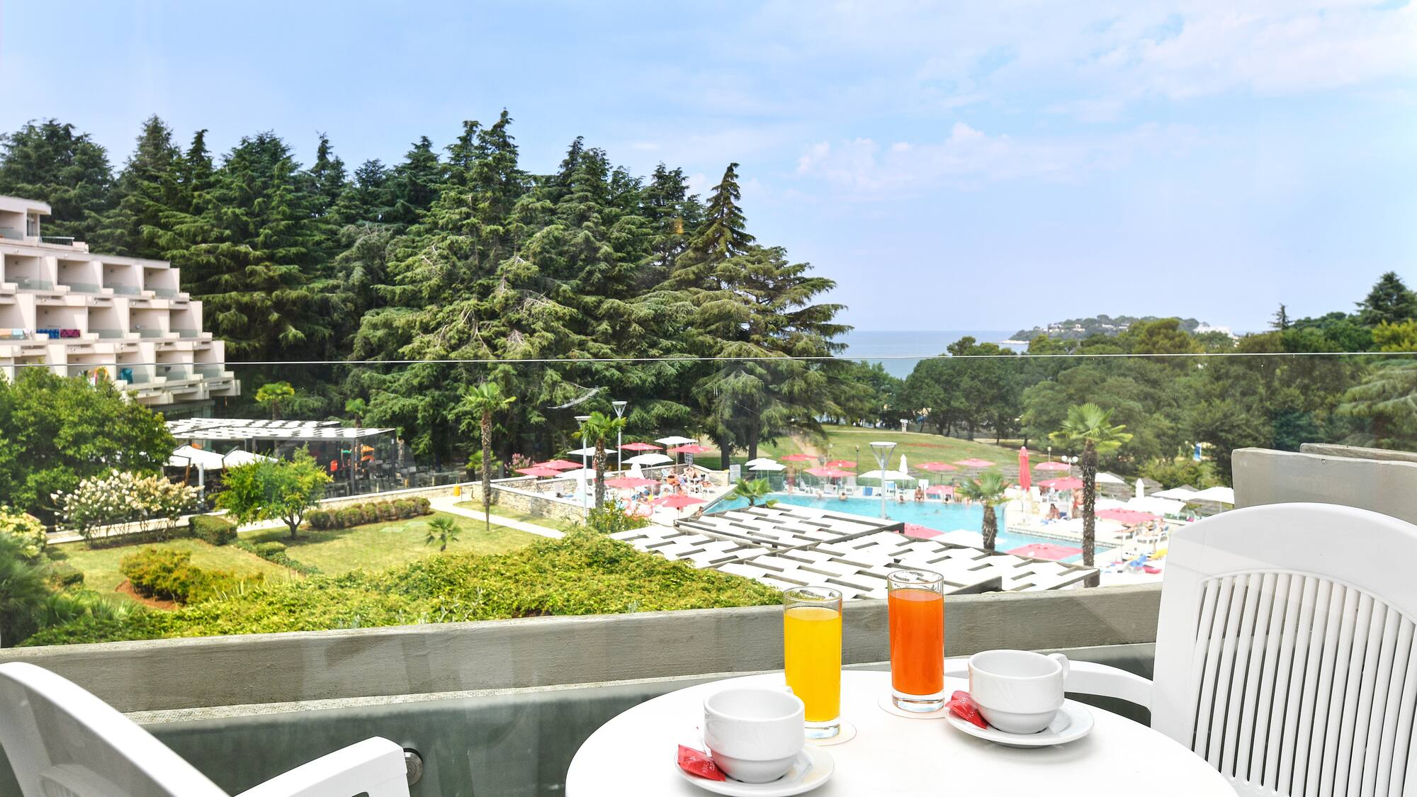 a table with a cup and saucer on it with a view of a pool and trees