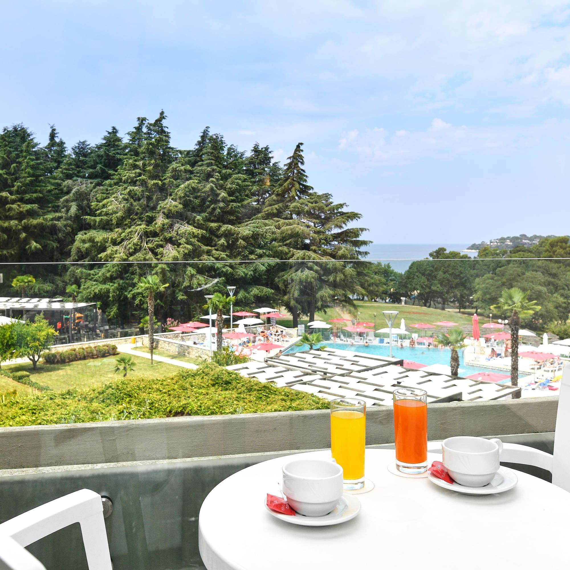 a table with a cup and saucer on it with a view of a pool and trees