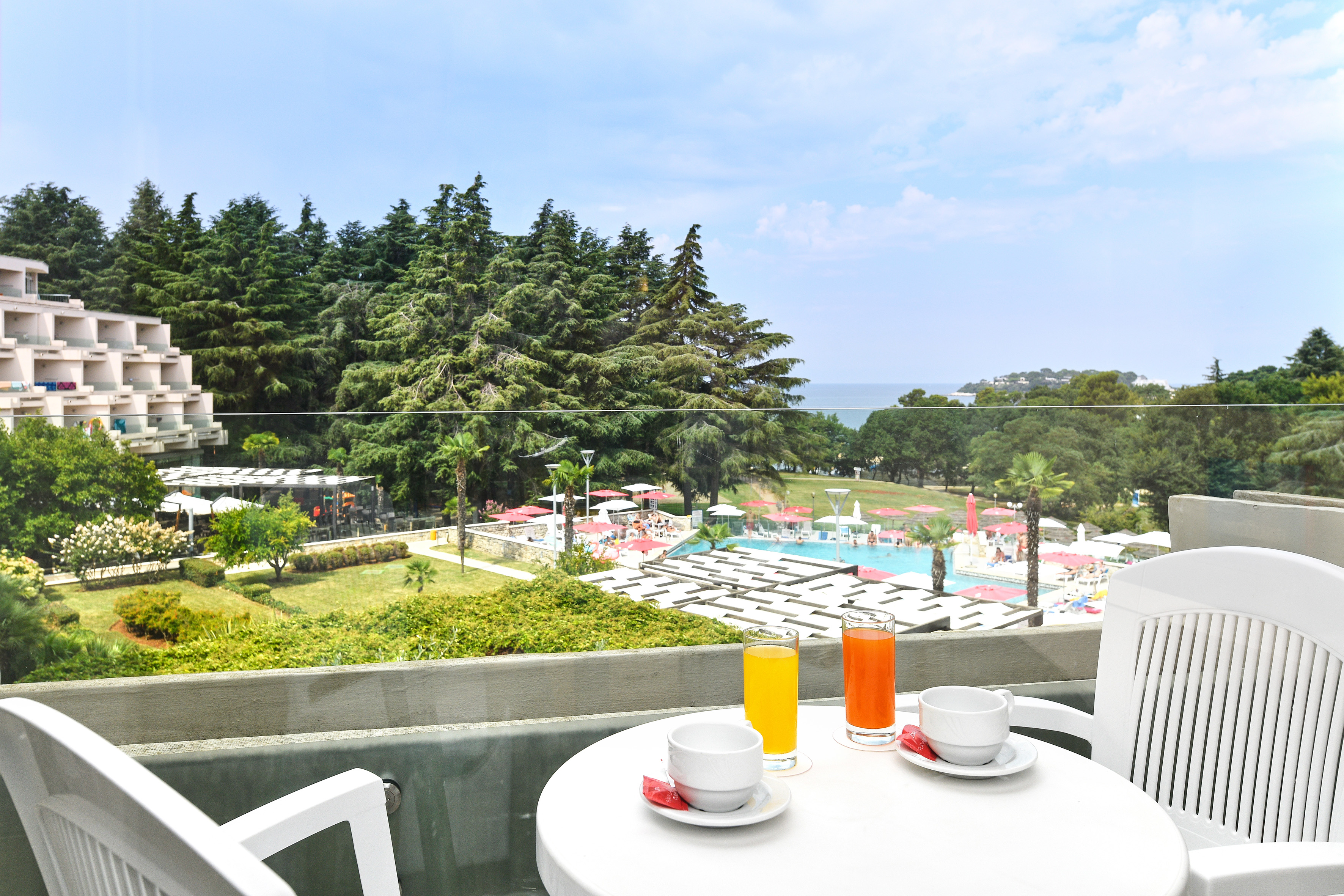 a table with a cup and saucer on it with a view of a pool and trees