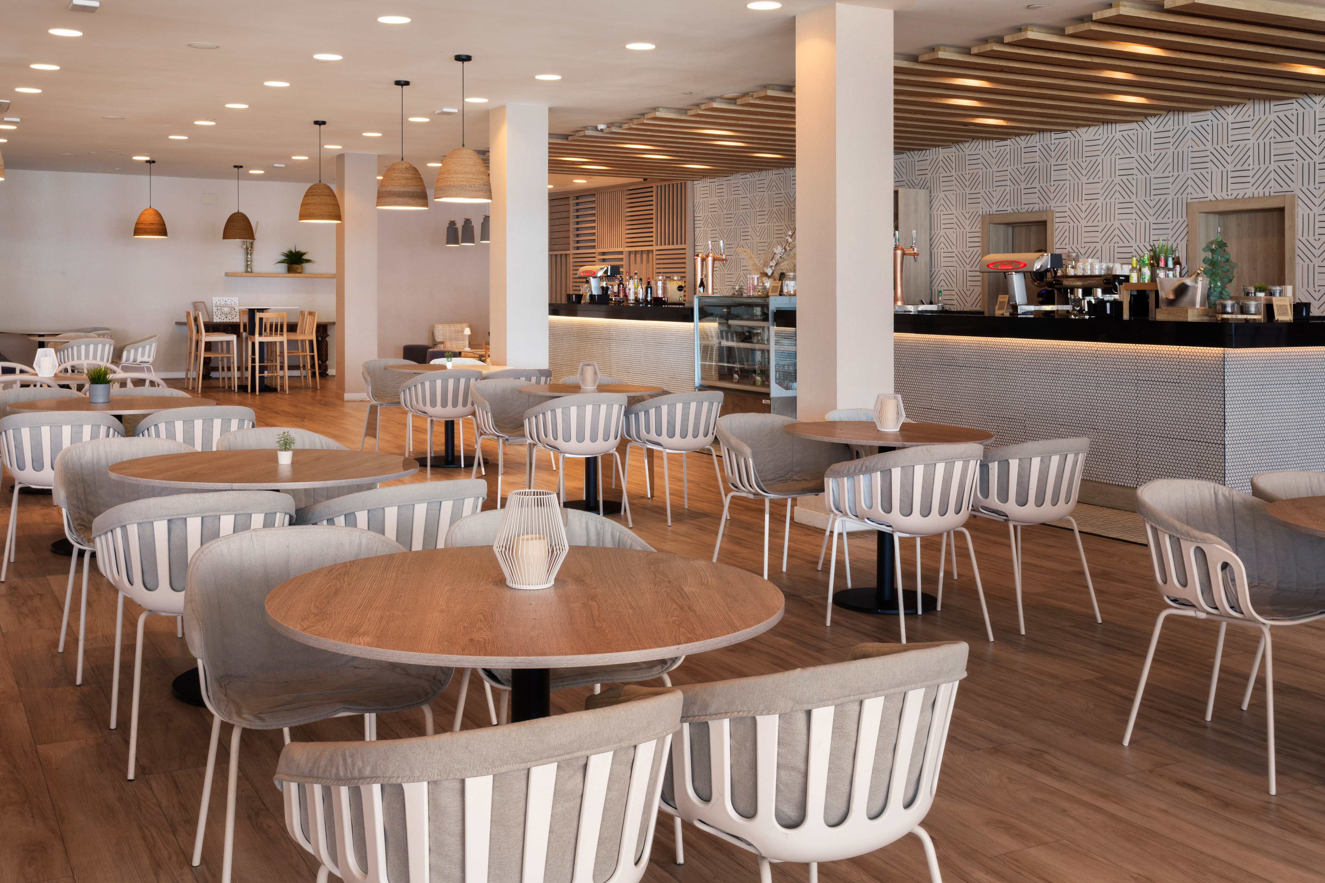 Modern restaurant with wooden tables, grey chairs, and stylish bar area.