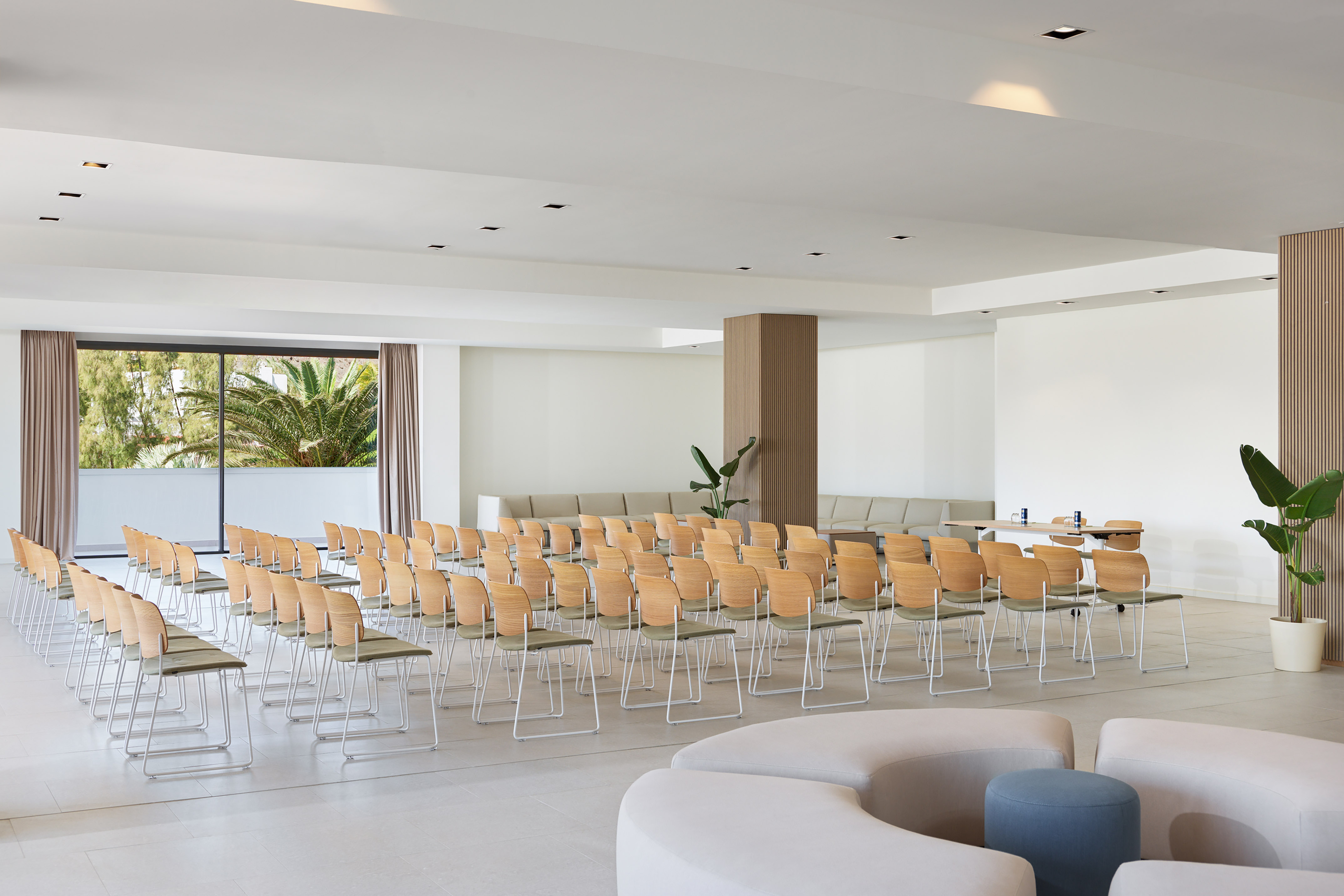 Bright, modern conference room with rows of chairs and tropical window view.