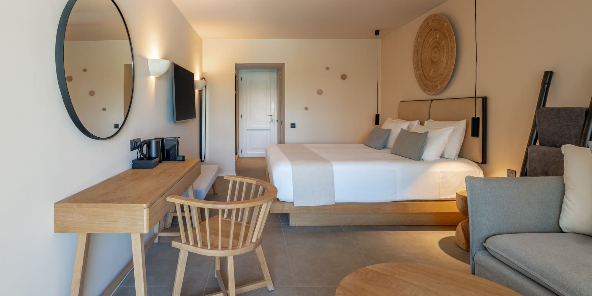 Minimalist hotel bedroom featuring king bed, wooden desk, and modern decor.
