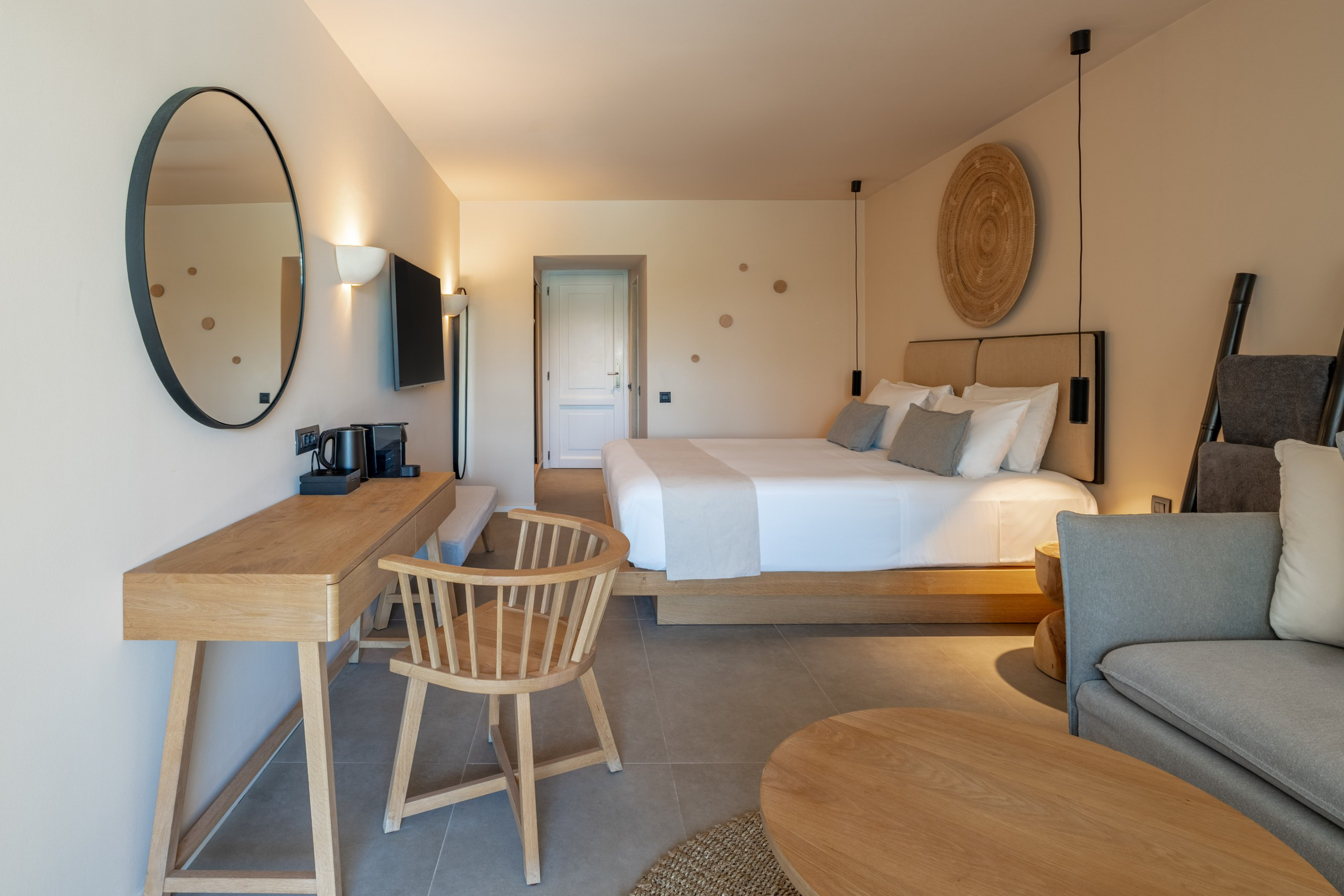 Minimalist hotel bedroom featuring king bed, wooden desk, and modern decor.