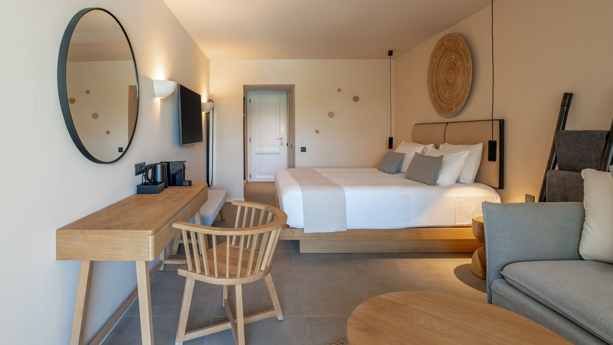 Minimalist hotel bedroom featuring king bed, wooden desk, and modern decor.
