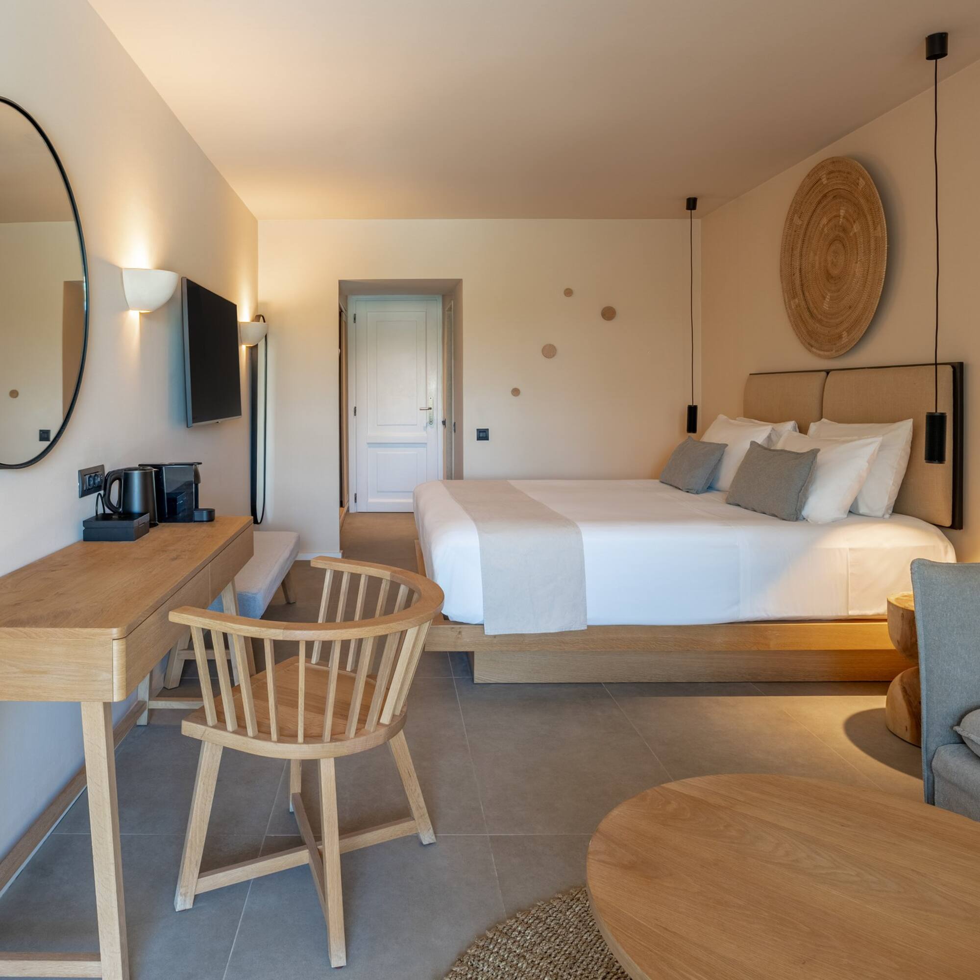 Minimalist hotel bedroom featuring king bed, wooden desk, and modern decor.