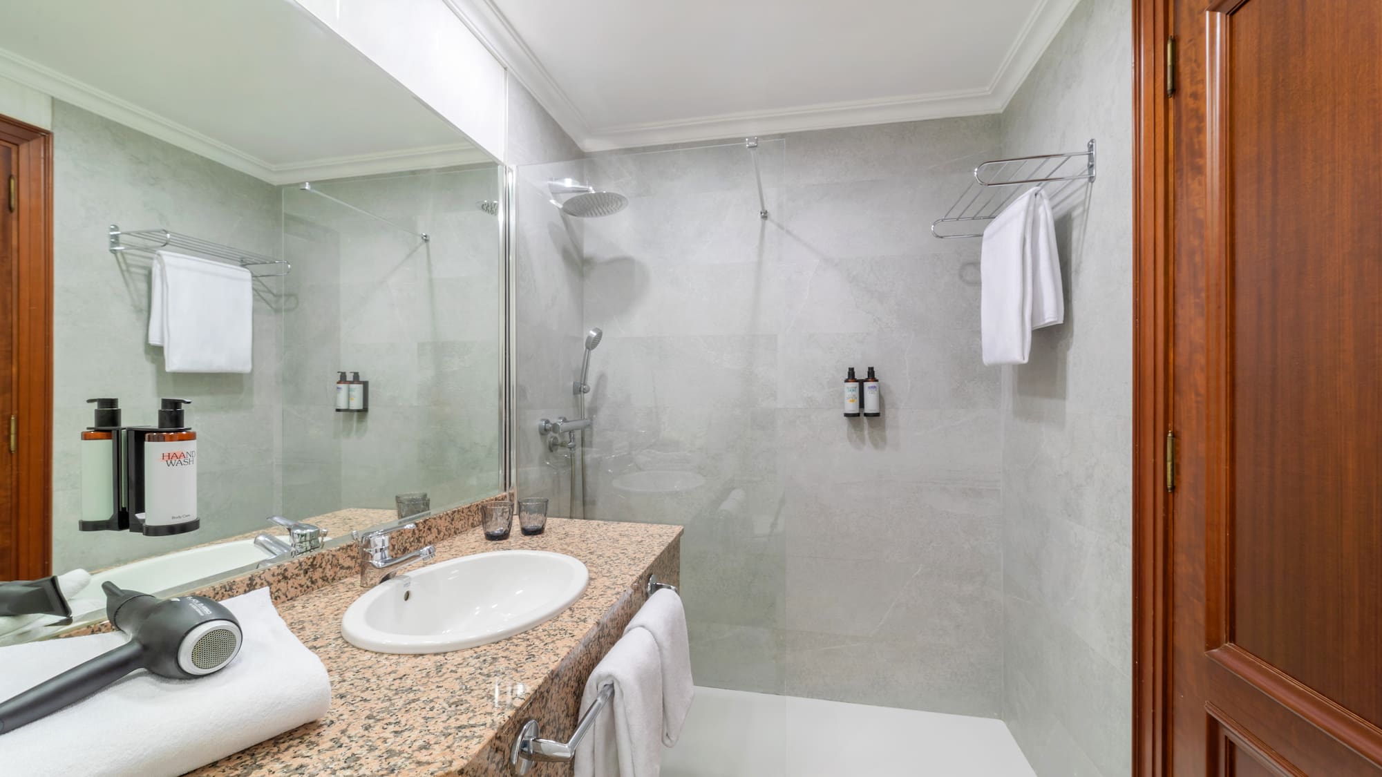Clean modern bathroom with walk-in shower, granite vanity, and hairdryer.