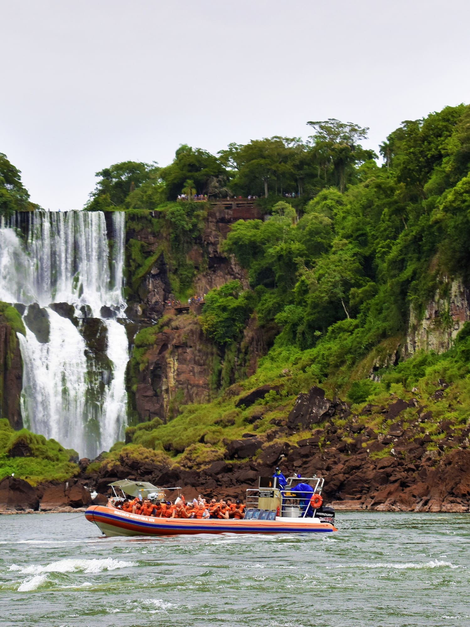 a boat with people in it in front of a waterfall