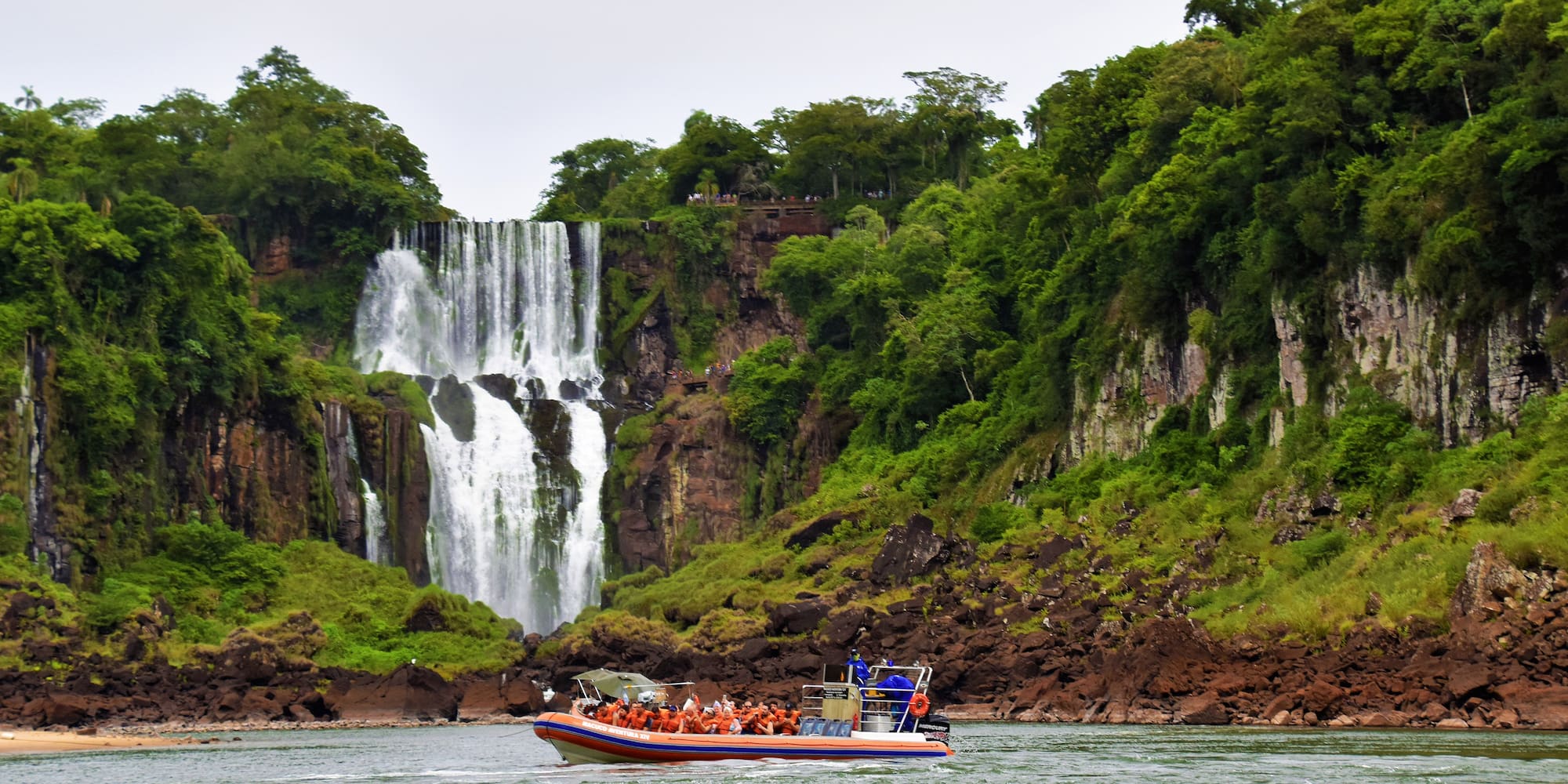 a boat with people in it in front of a waterfall