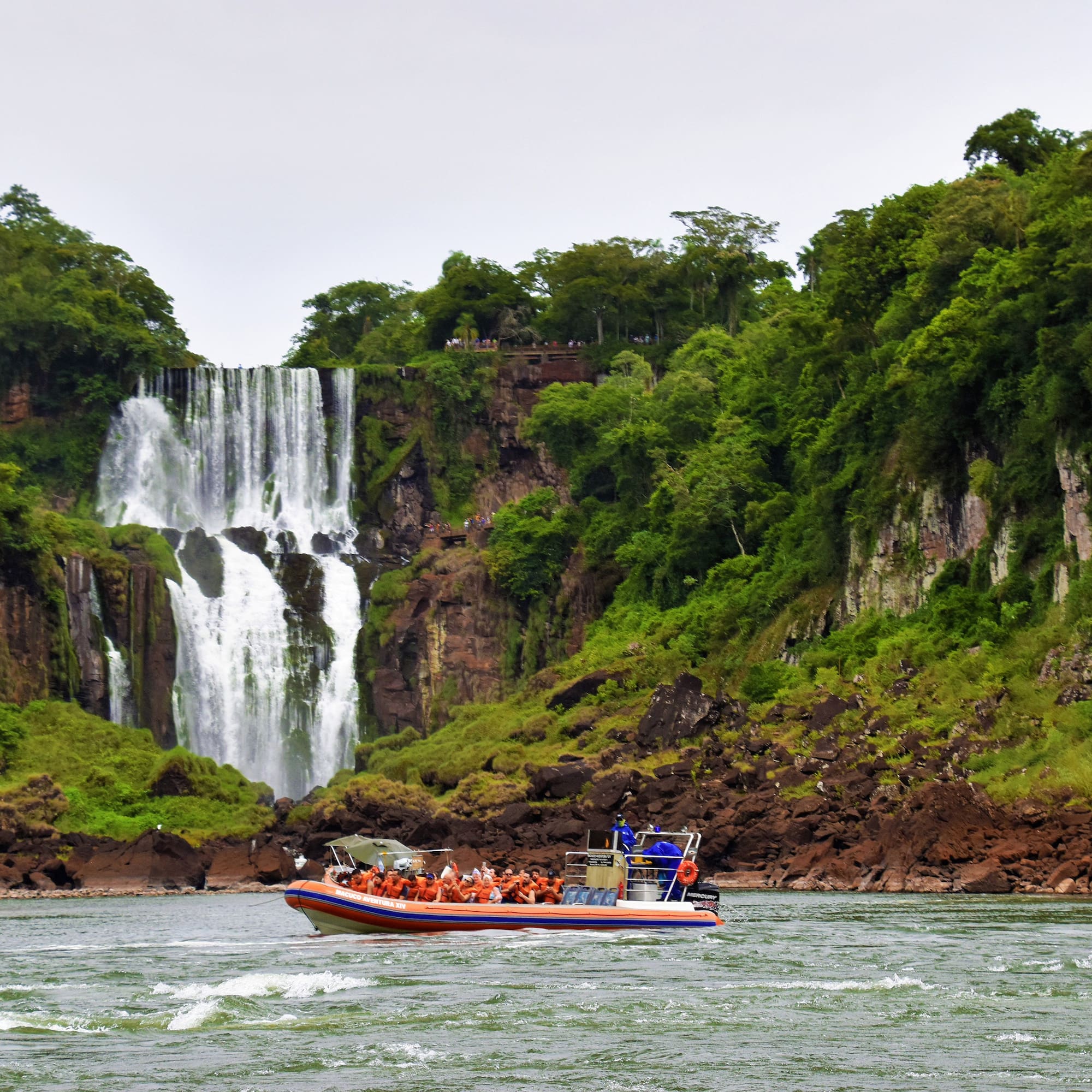 a boat with people in it in front of a waterfall