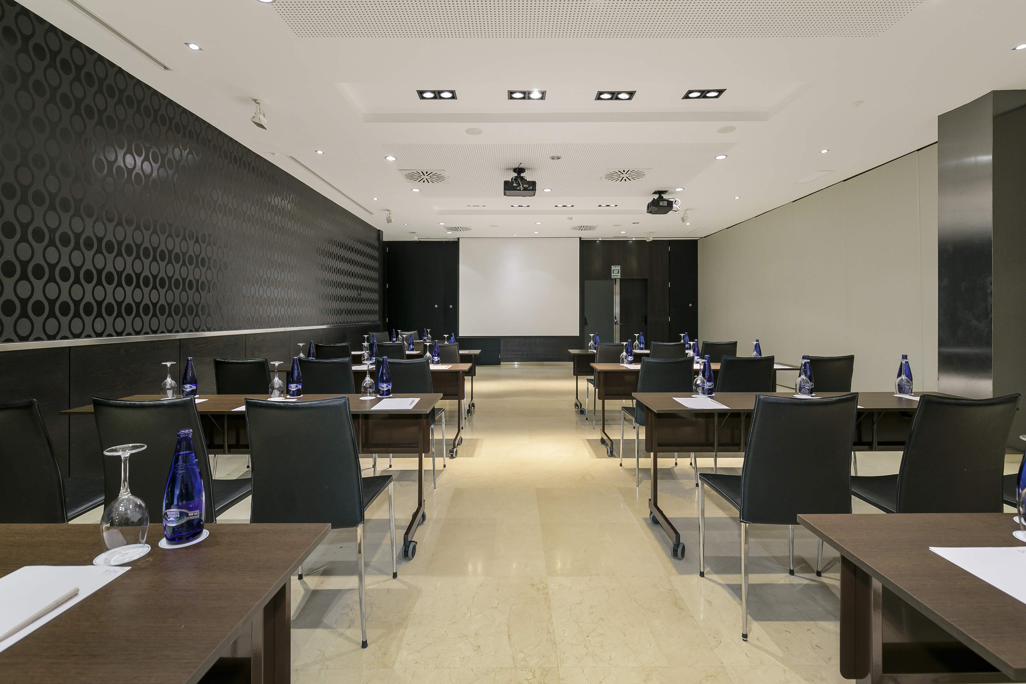 Empty modern meeting room with rows of tables, chairs, projector screen.