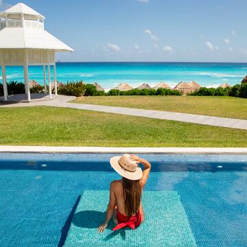 a woman sitting in a pool with a gazebo overlooking the ocean